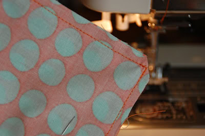 red, blue and coral fabric during construction process with sewing notions
