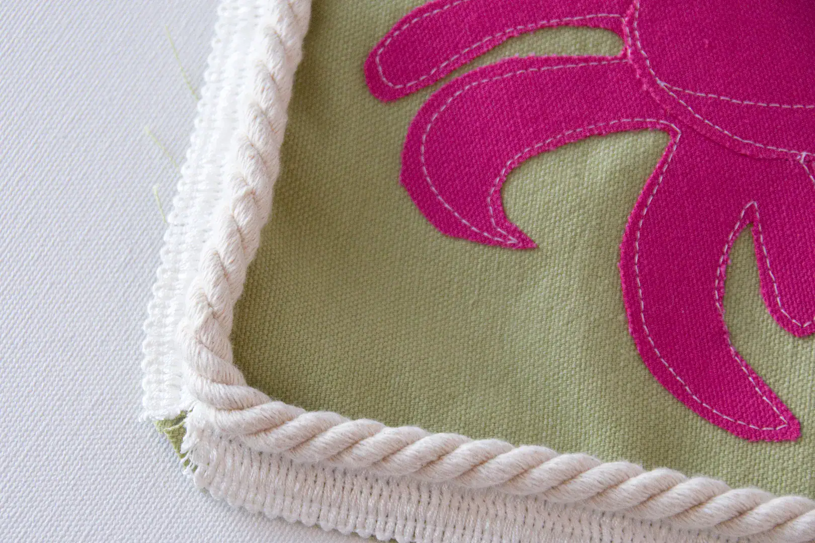 Three pillows on an outdoor couch, blue, green and green with a pink crab