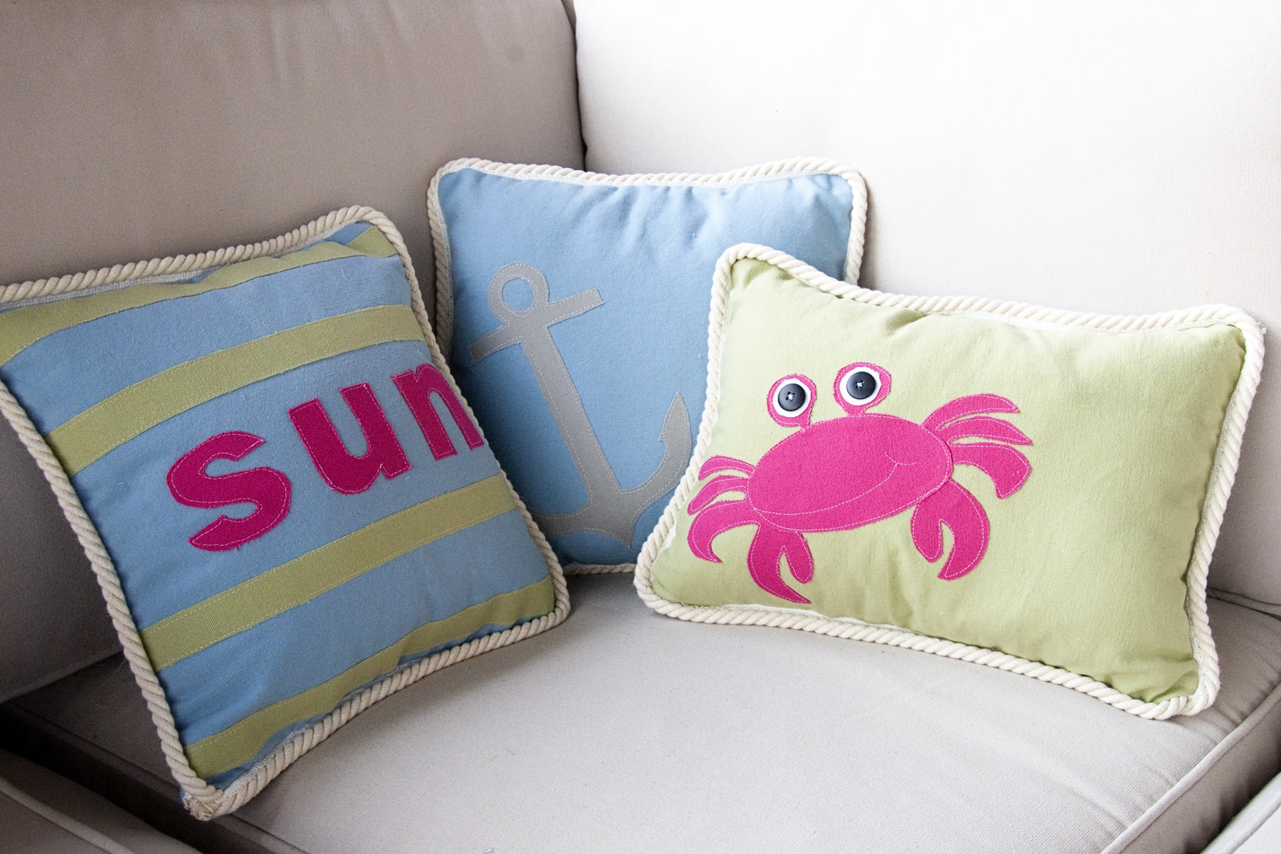 Three pillows on outdoor sofa, blue, and green with a crab