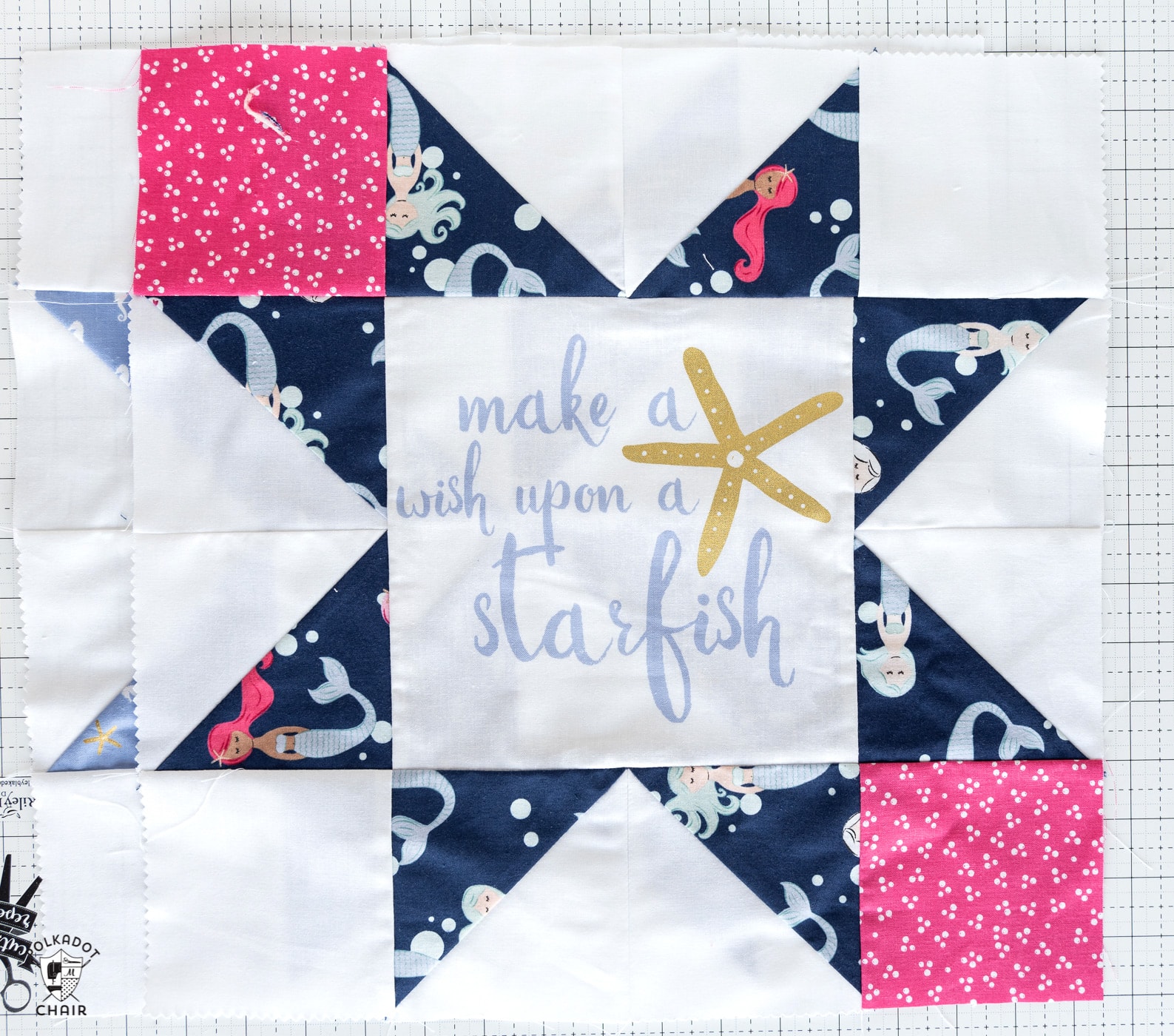 star quilt block with navy and pink and a word in the center on white cutting mat