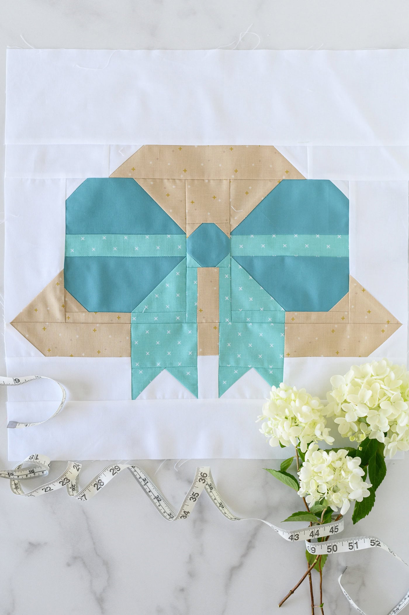 Beach hat quilt block on marble table with hydrangeas