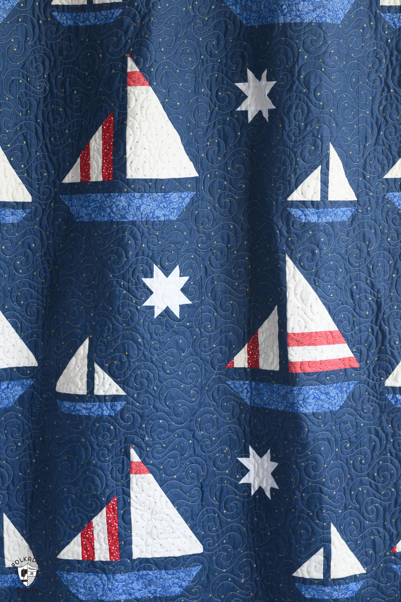 navy blue sailboat quilt hanging on wall in room
