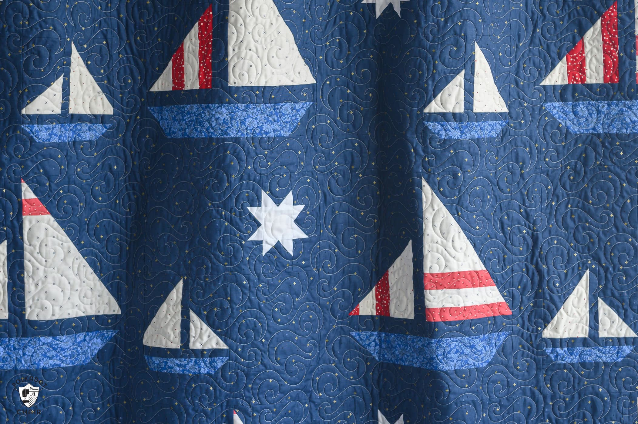 navy blue sailboat quilt hanging on wall in room