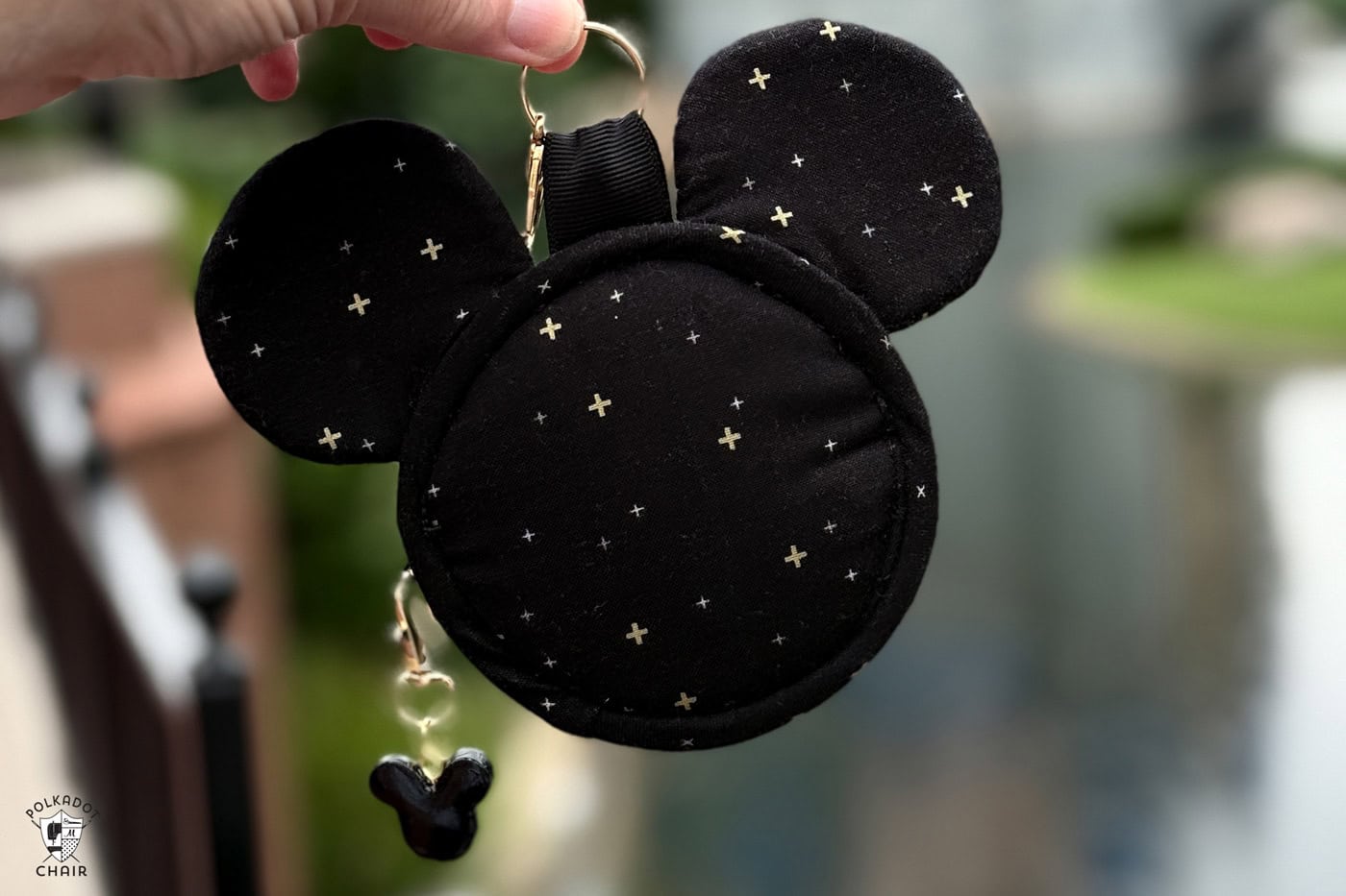 hand holding mickey head shaped bag charm outdoors