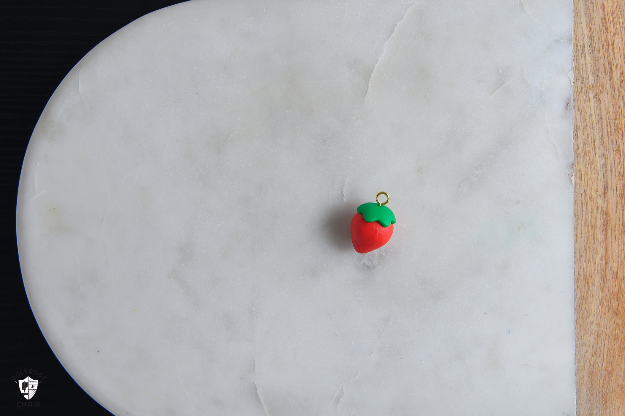 red and green clay simple strawberry with gold loop at the top.