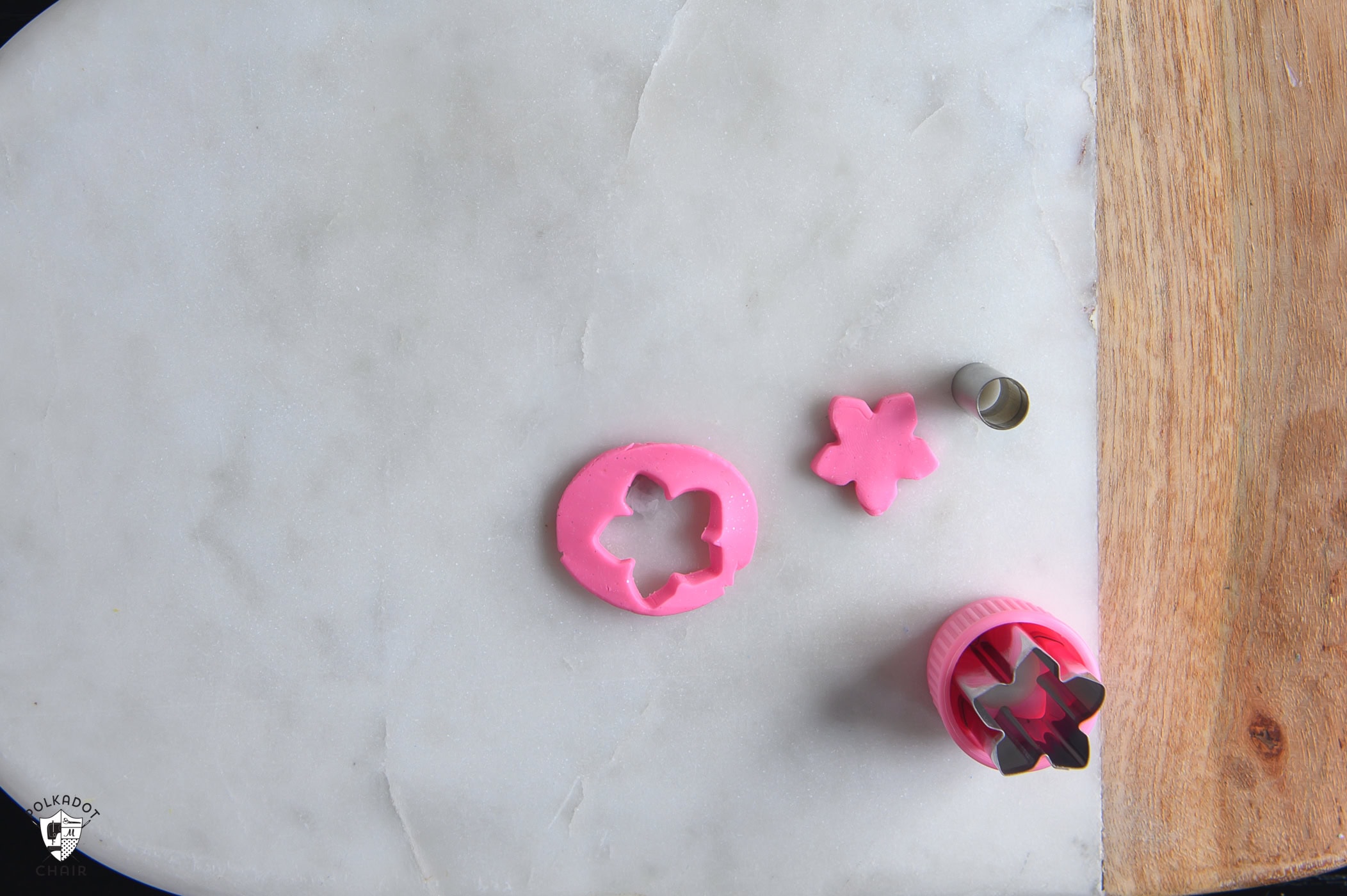 pink clay that has been cut out of with a flower shaped cookie cutter.