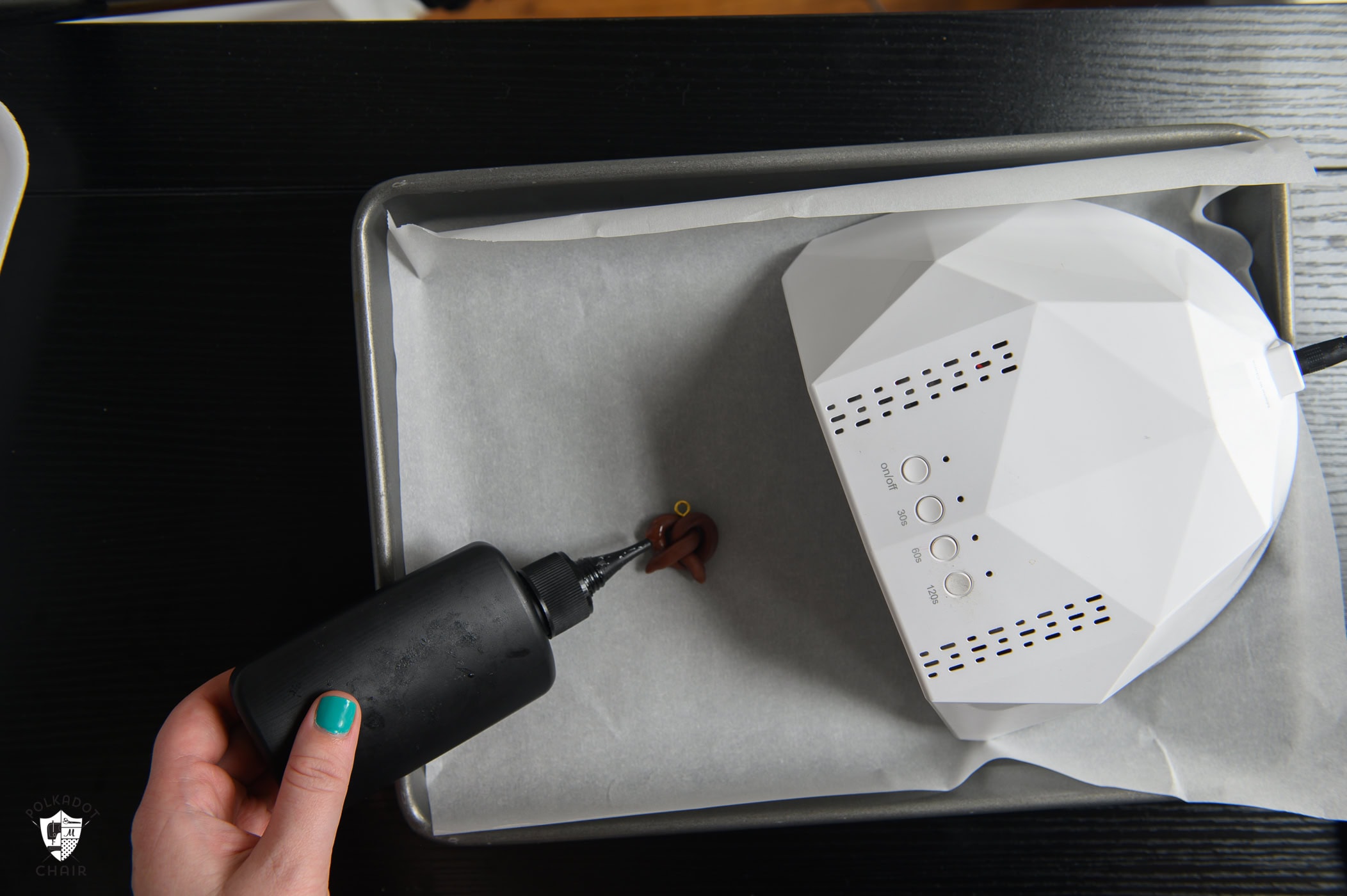 bottle of UV resin going on clay pretzel with UV lamp turned off.