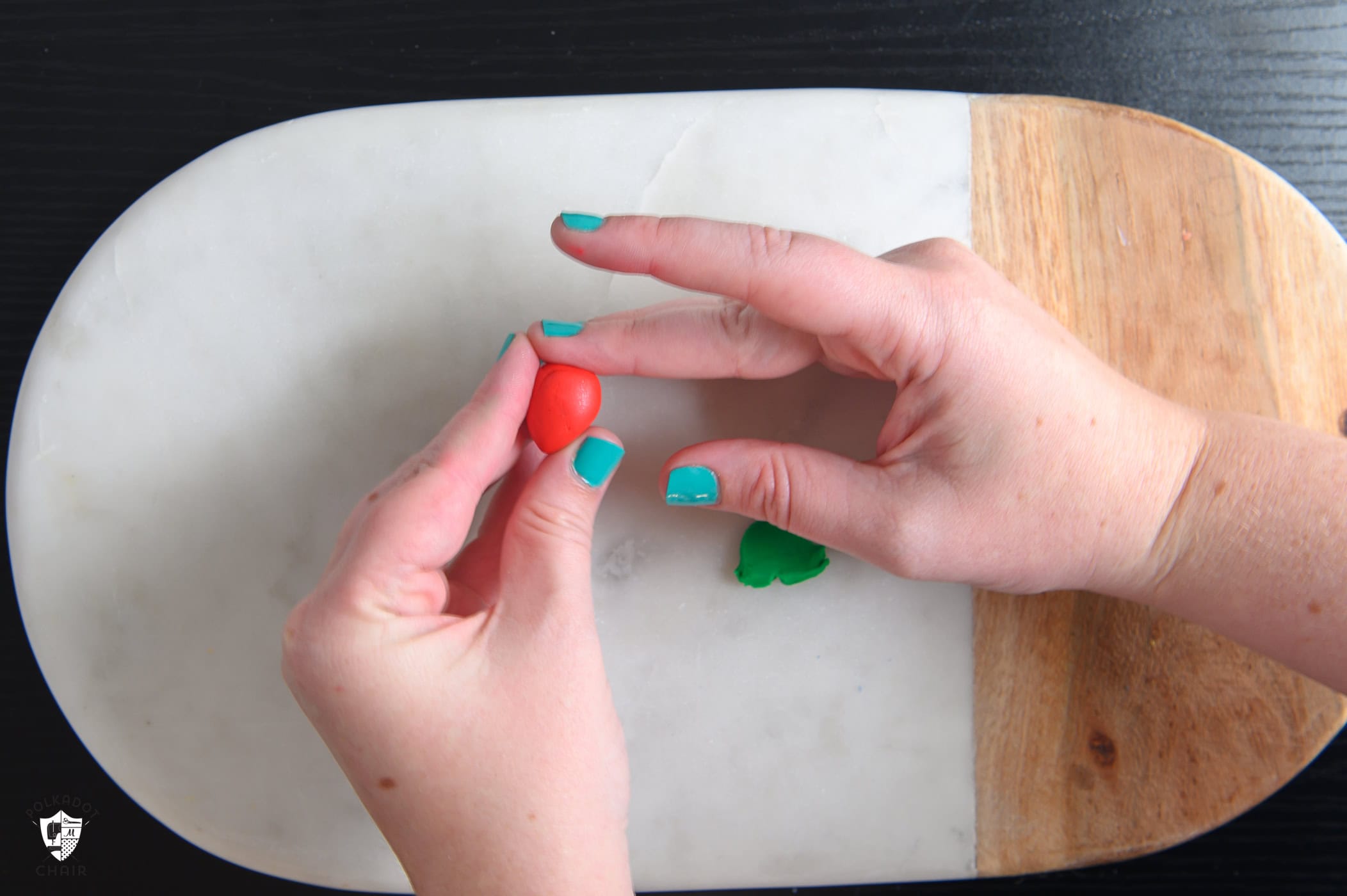 hands molding red clay into a strawberry shape.
