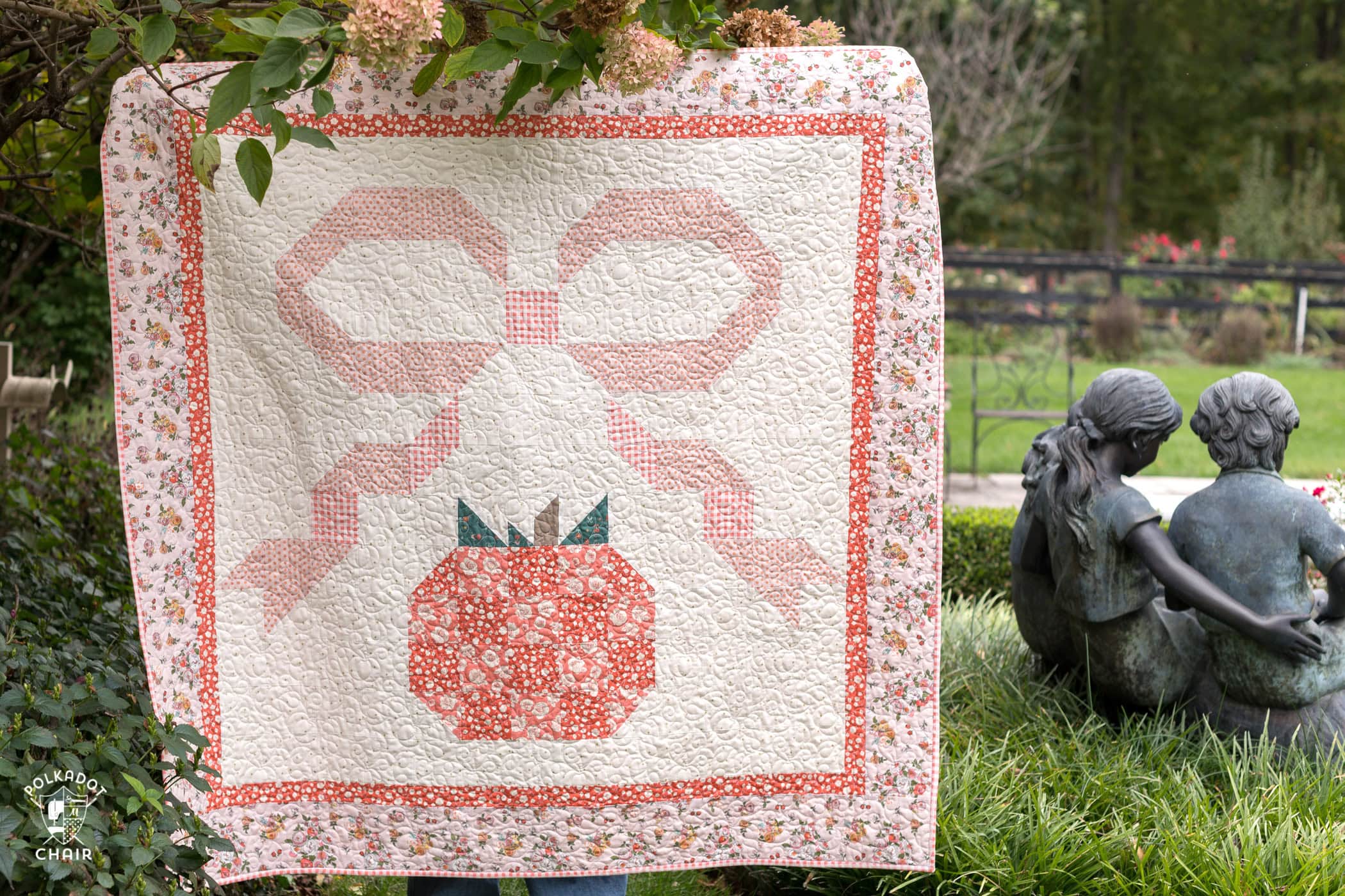 quilt with pumpkin and bow outdoors - quilt is pink, orange and coral