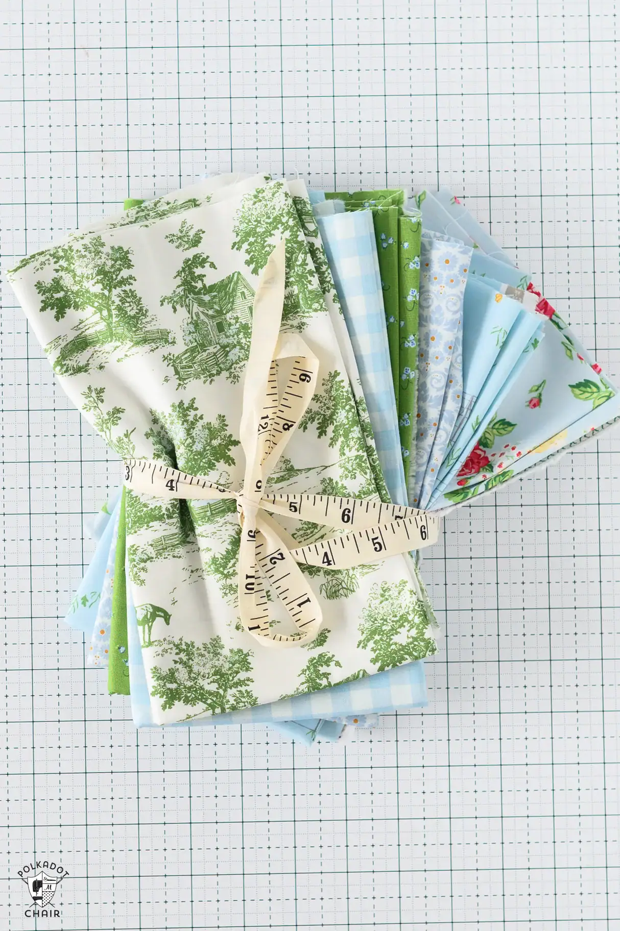 blue and green fabric bundle on white cutting mat