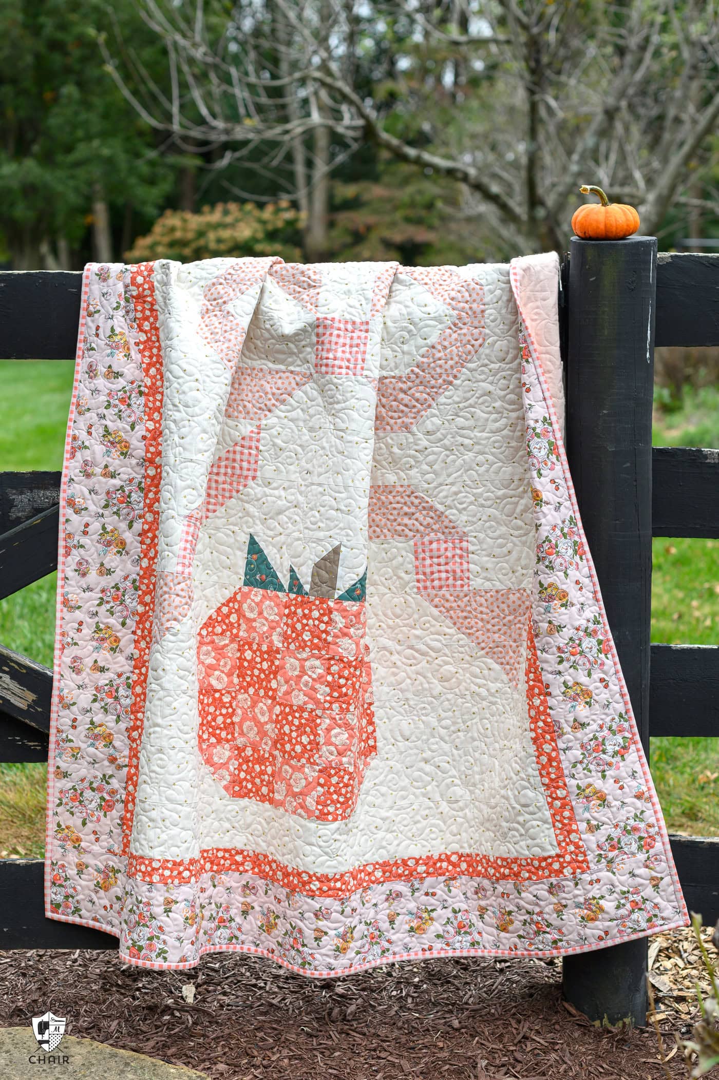 quilt with pumpkin and bow outdoors - quilt is pink, orange and coral