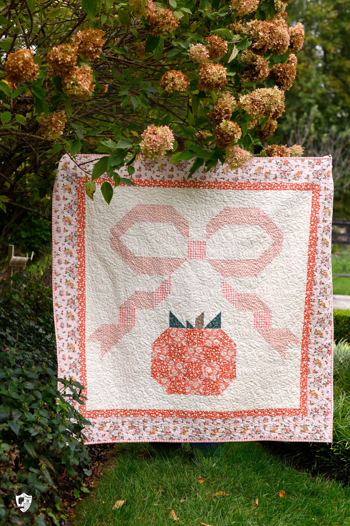 quilt with pumpkin and bow outdoors - quilt is pink, orange and coral
