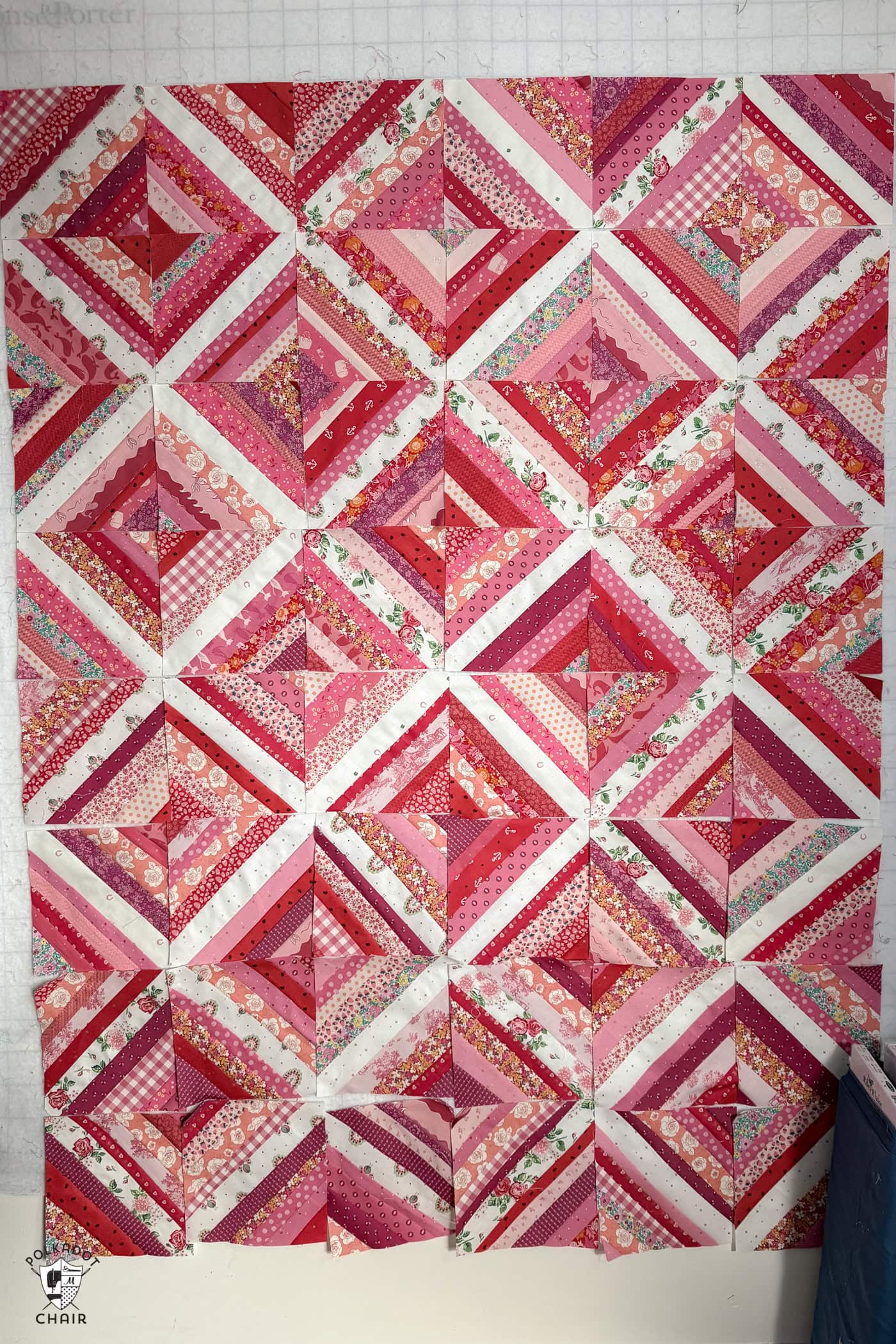 red, pink and white string quilt blocks on white wall