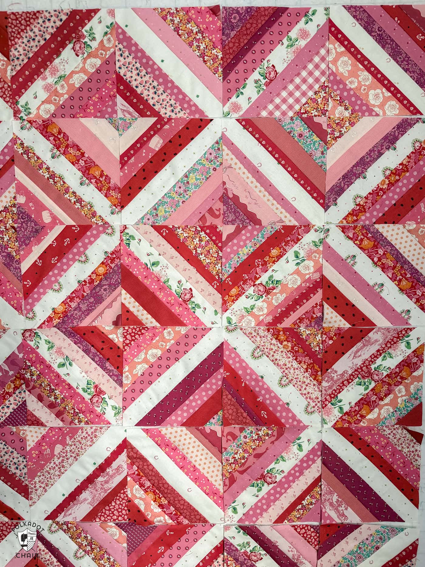 red, pink and white string quilt blocks on white wall