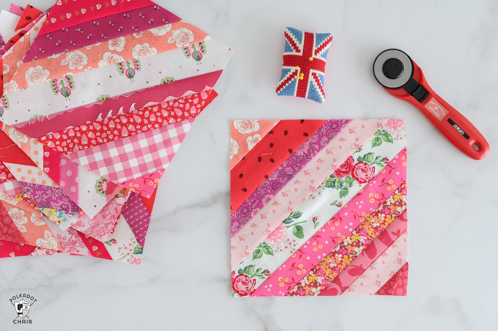 Red, pink and white string quilt blocks on white countertop with sewing notions