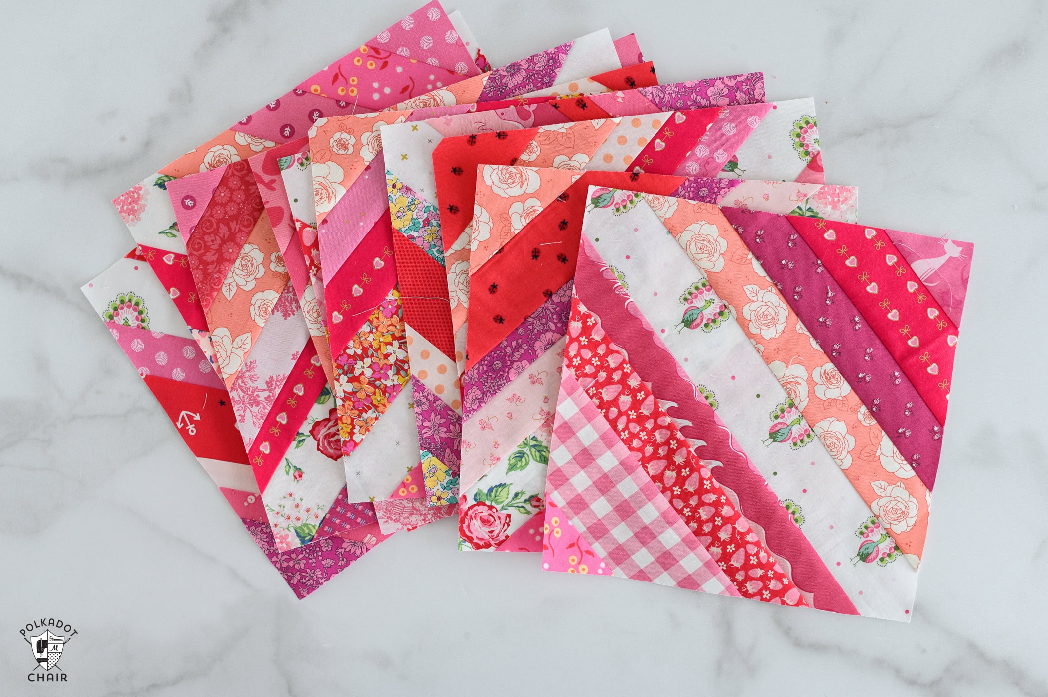 Red, pink and white string quilt blocks on white countertop with sewing notions