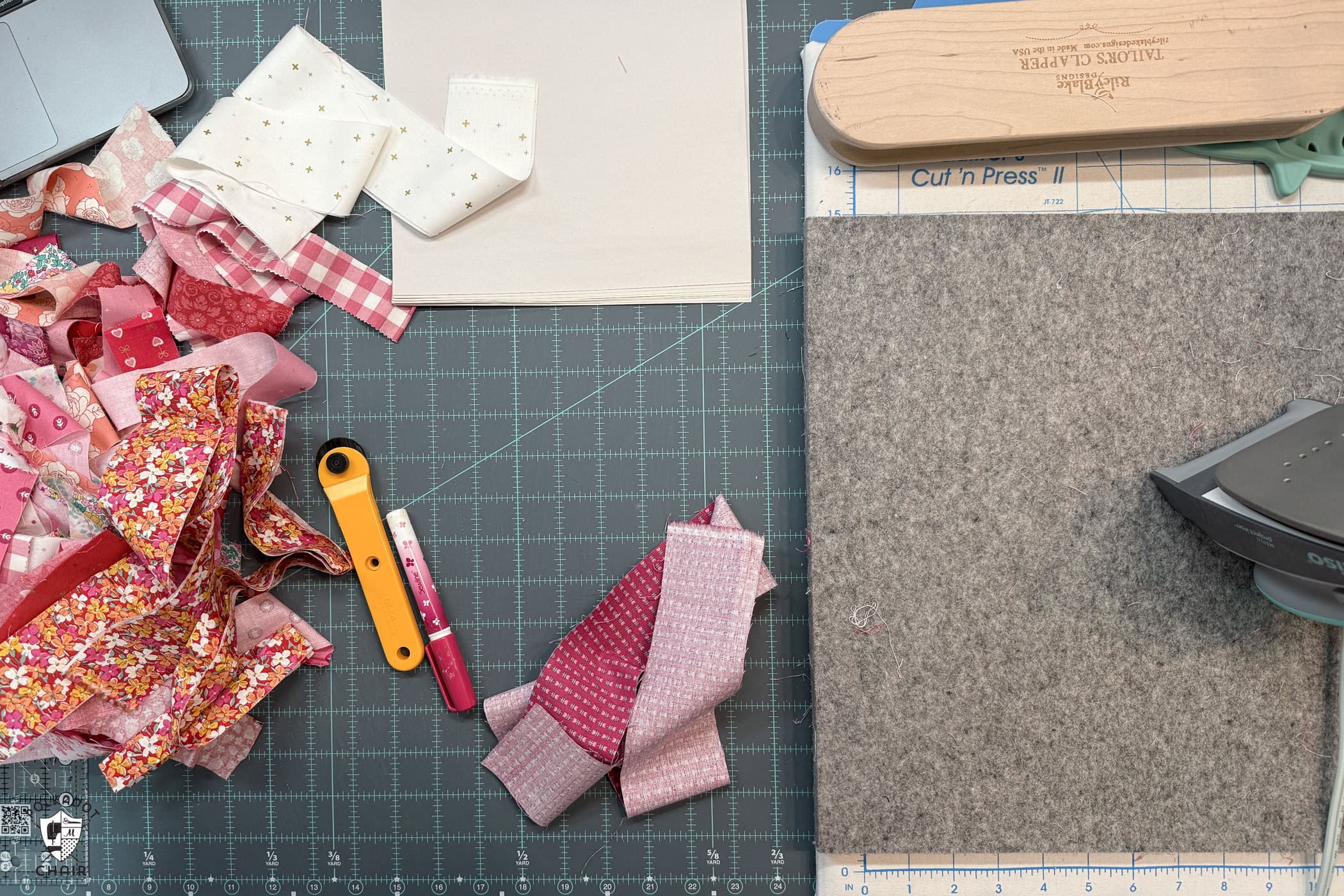pressing mat, iron and fabric scraps on table with blue cutting mat