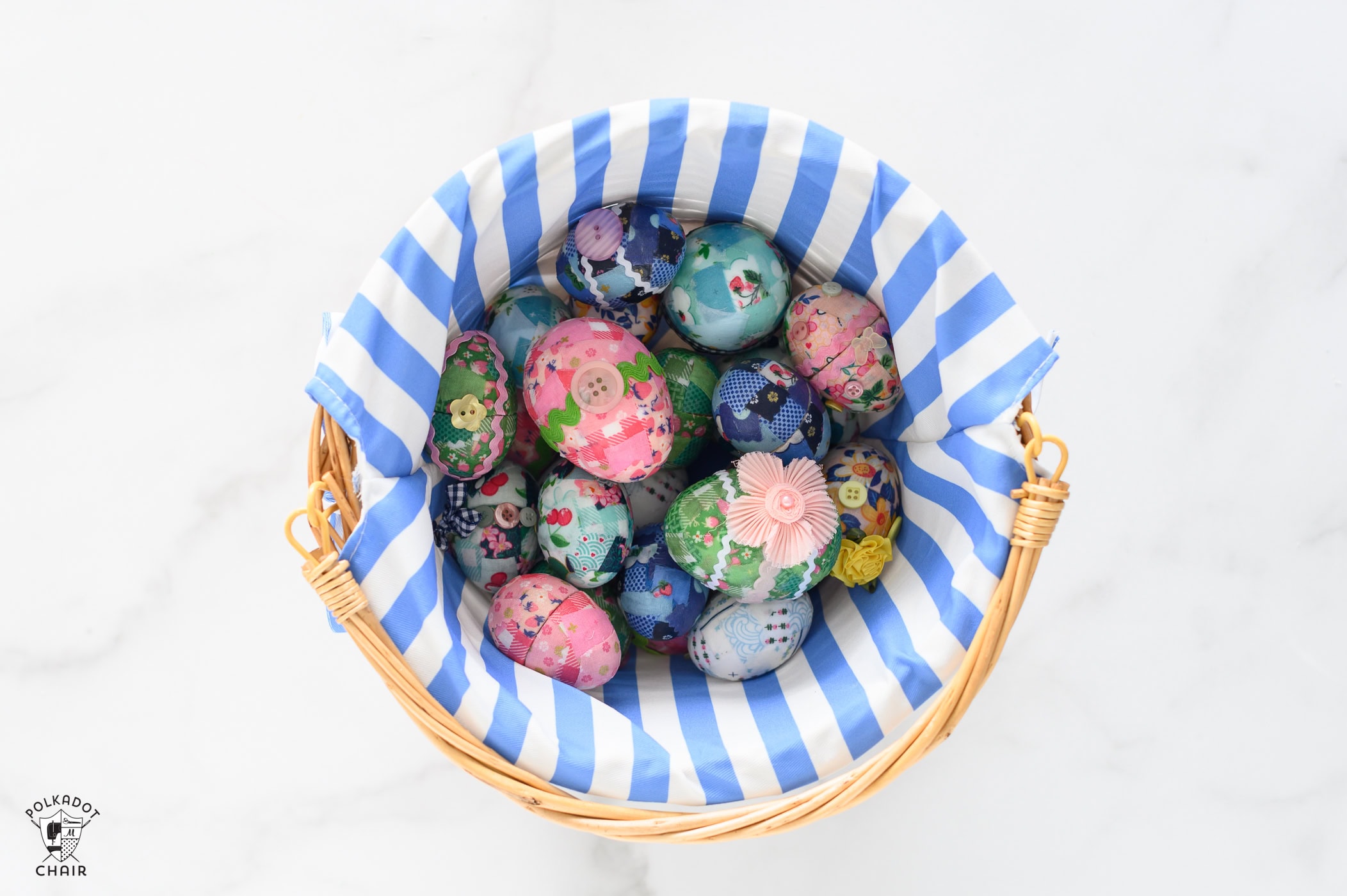 basket with blue and white striped lining filled with blue pink and green fabric covered easter eggs decorated with buttons and ricrac.