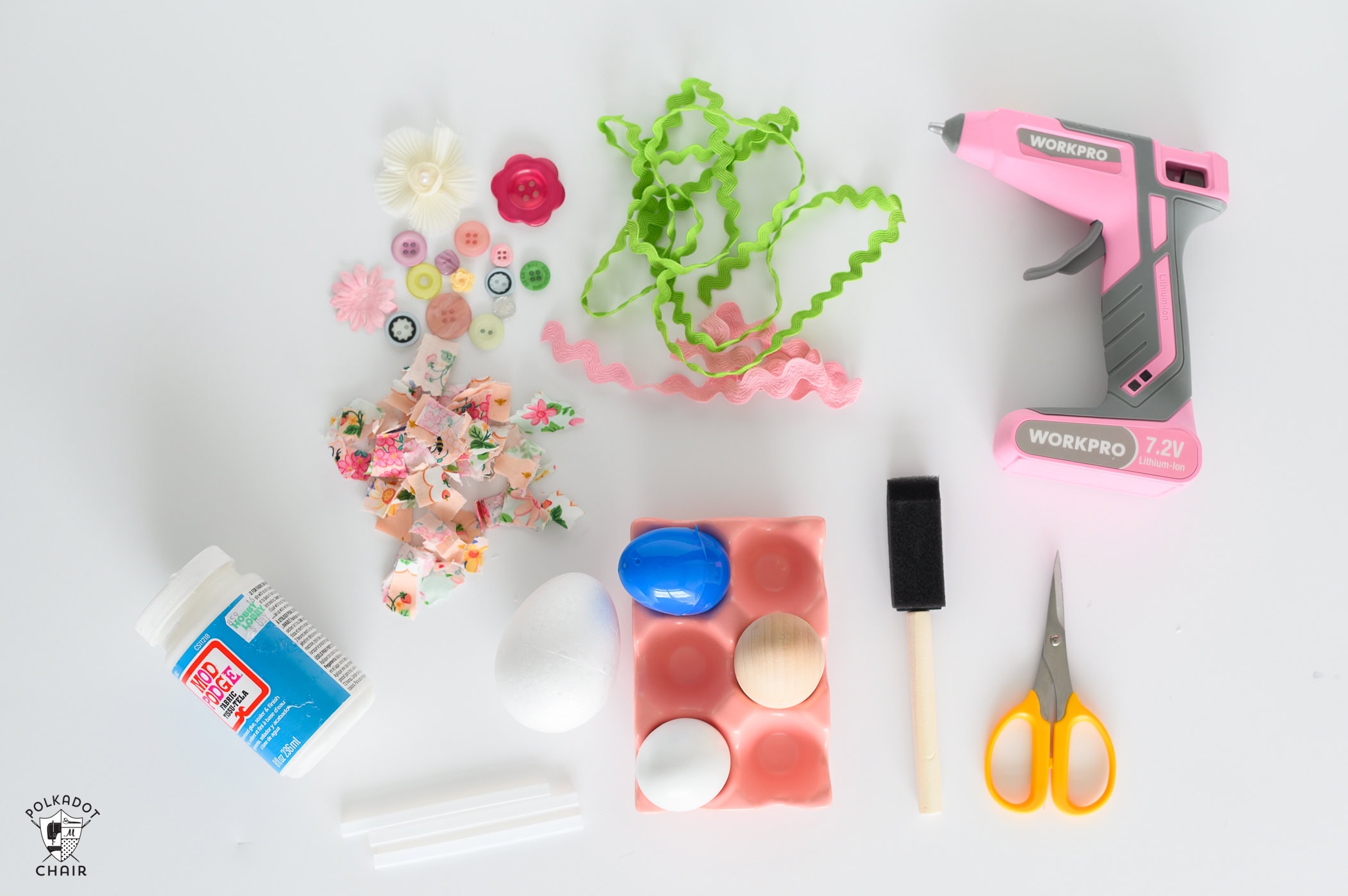 pink egg carton with a blue, white, and brown faux egg. green ricrac. pink hot glue gun. cut up pieced of pink fabric. yellow scissors. black foam paint brush. modgepodge bottle.