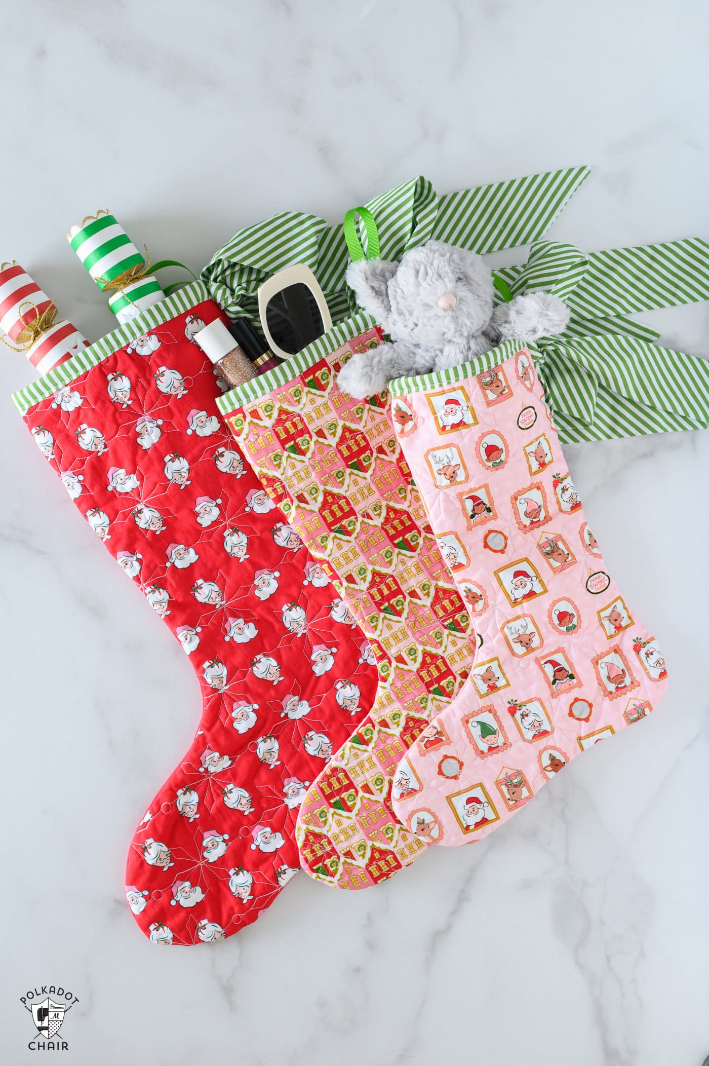 Three quilted christmas stockings on white table with toys and candy