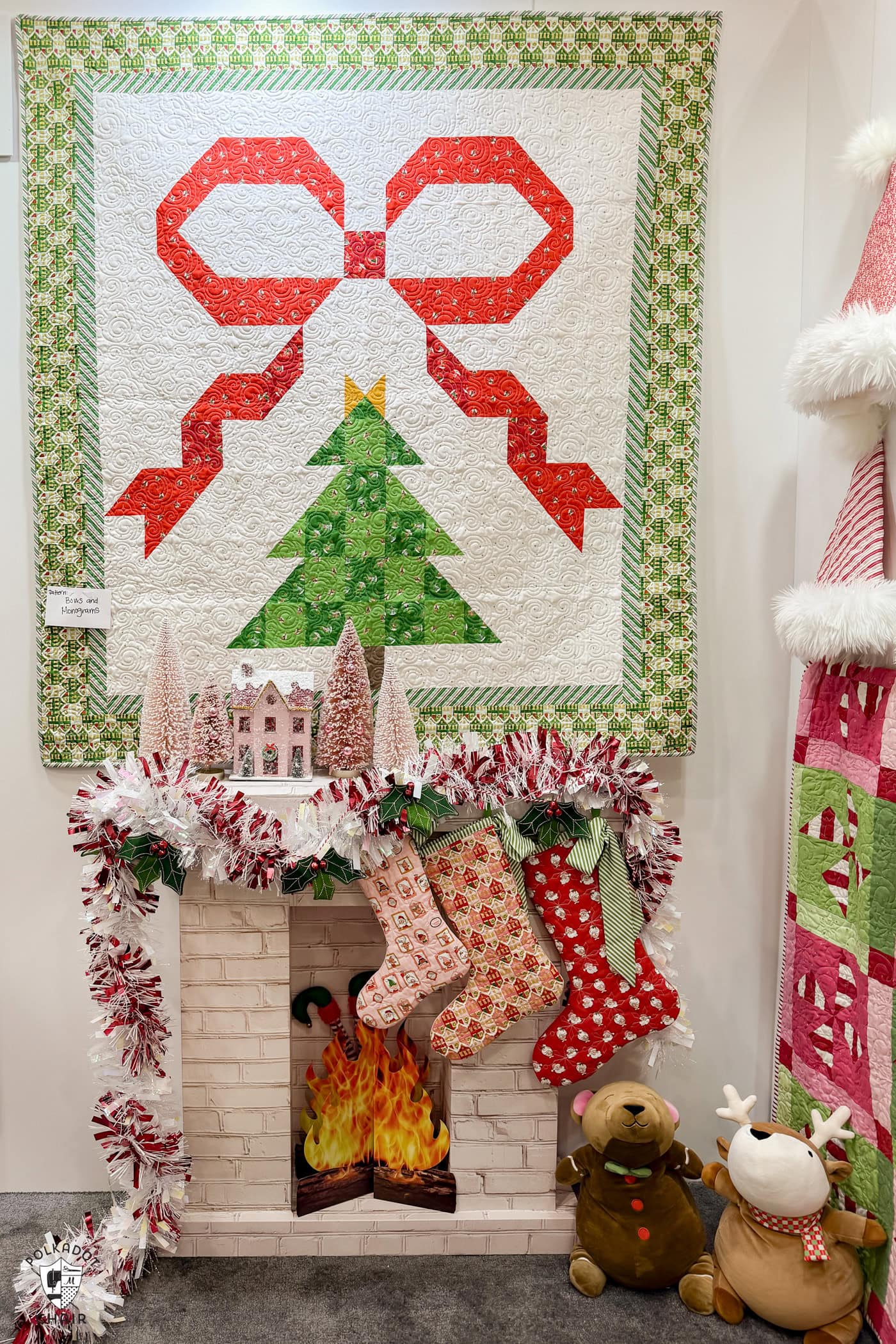 photo of booth at quilt market featuring a variety of christmas quilts