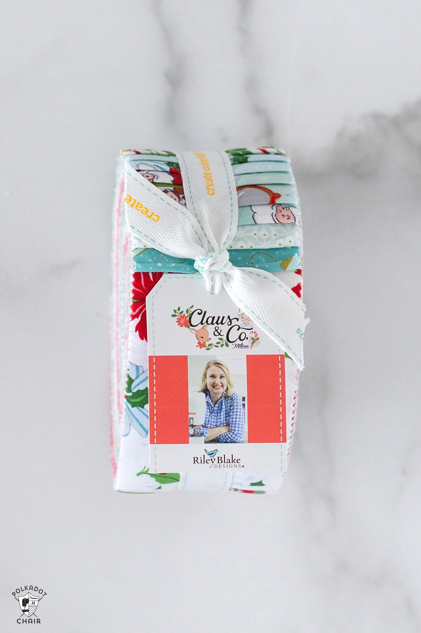 2 1/2 precut roll of claus and co fabric on white marble table showing tag