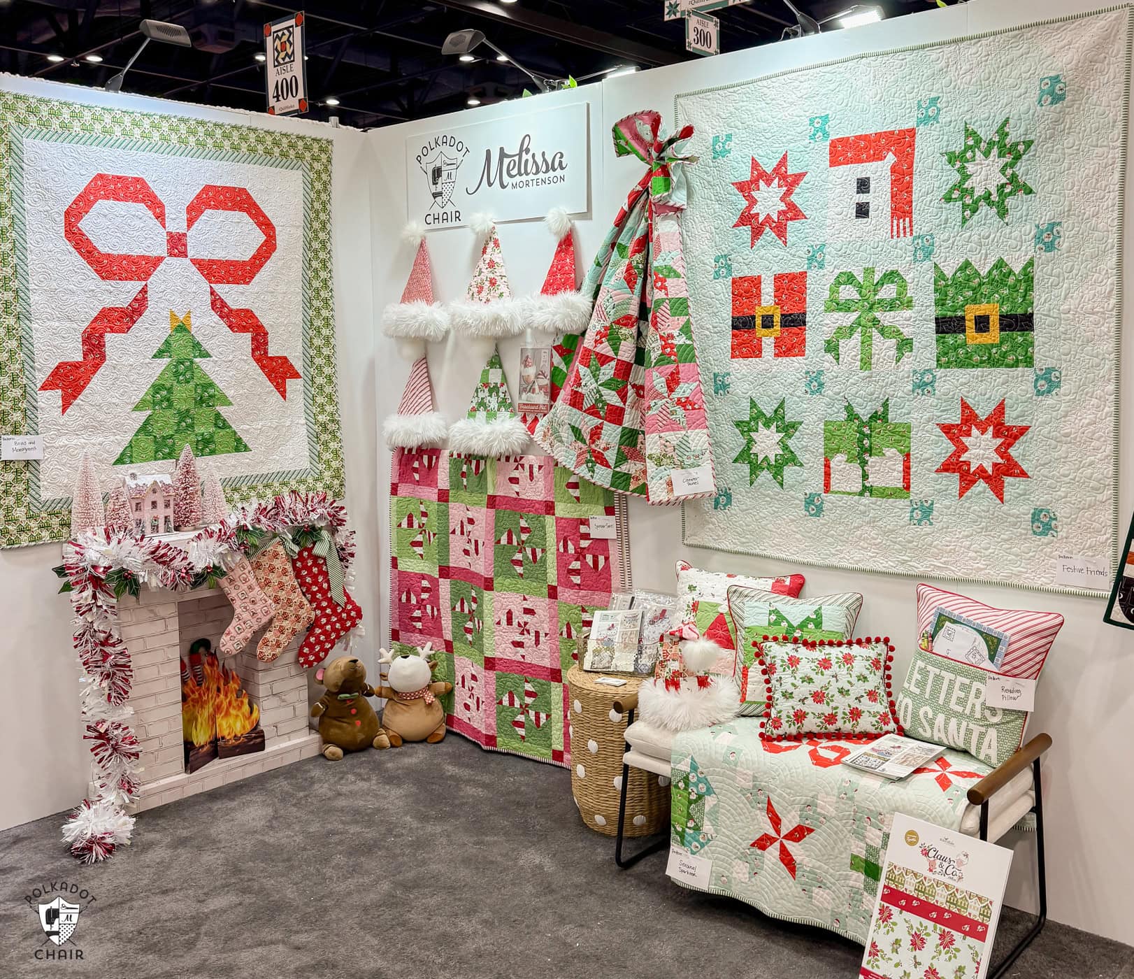 photo of booth at quilt market featuring a variety of christmas quilts