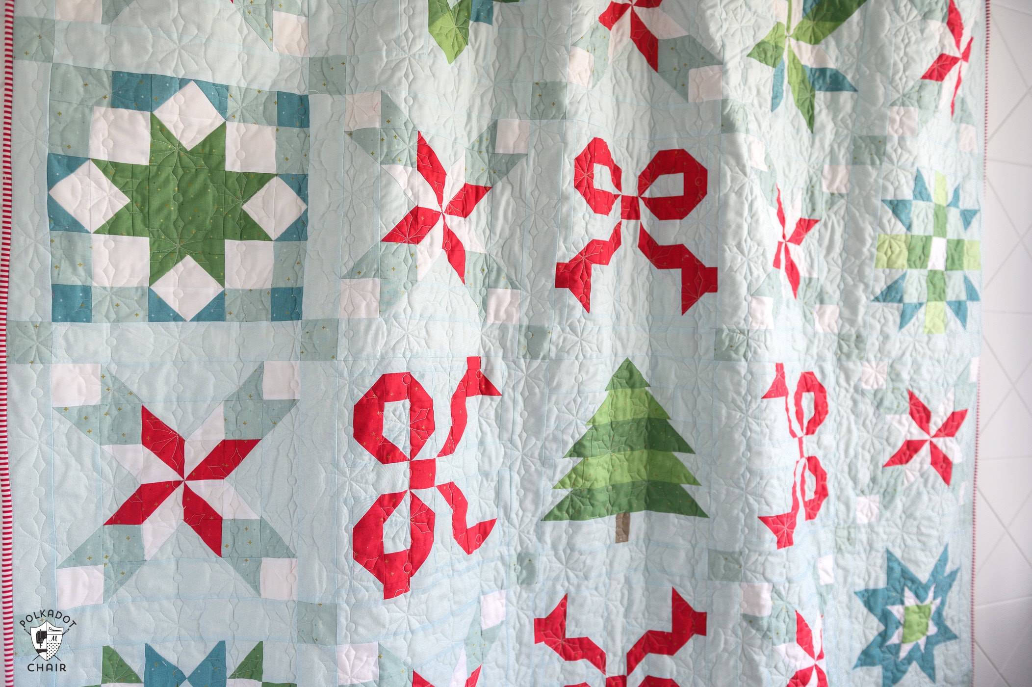 Christmas quilt featuring red, green, and blue holiday patterns and a Christmas tree design.