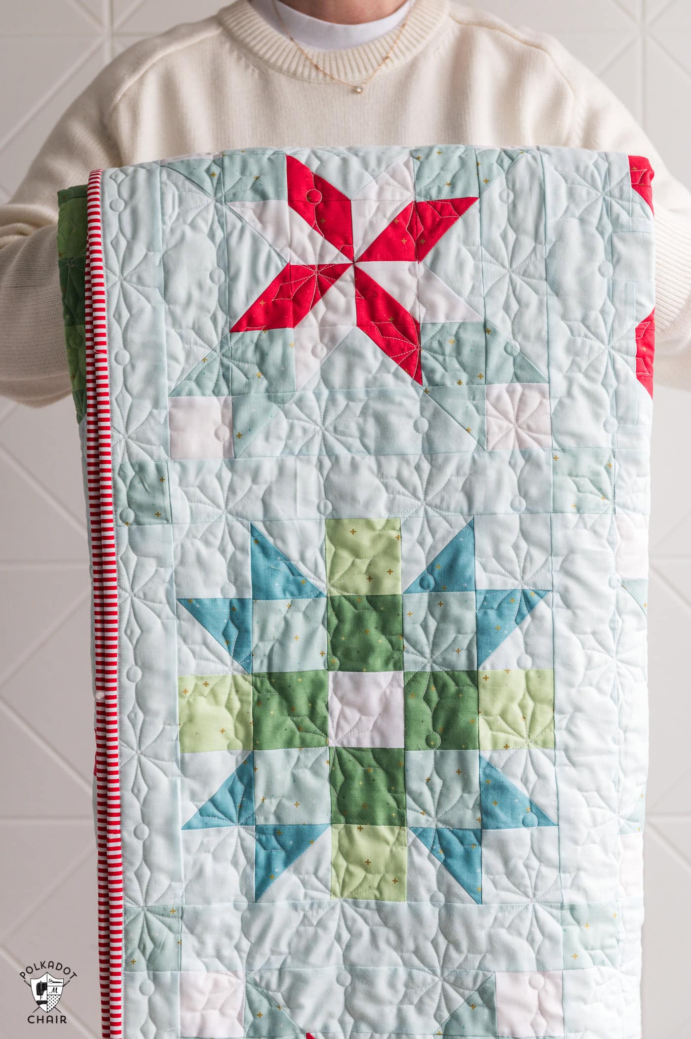 woman holding folded christmas quilt