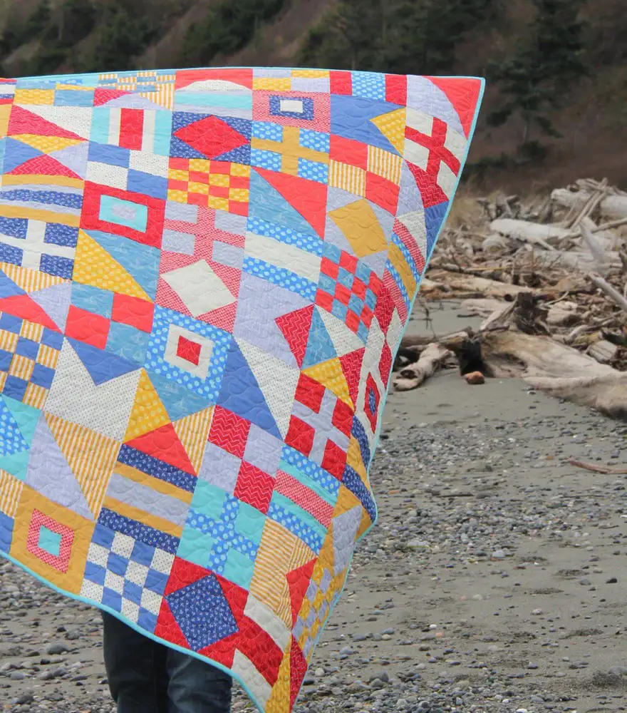 red, blue and yellow nautical flags quilt on beach