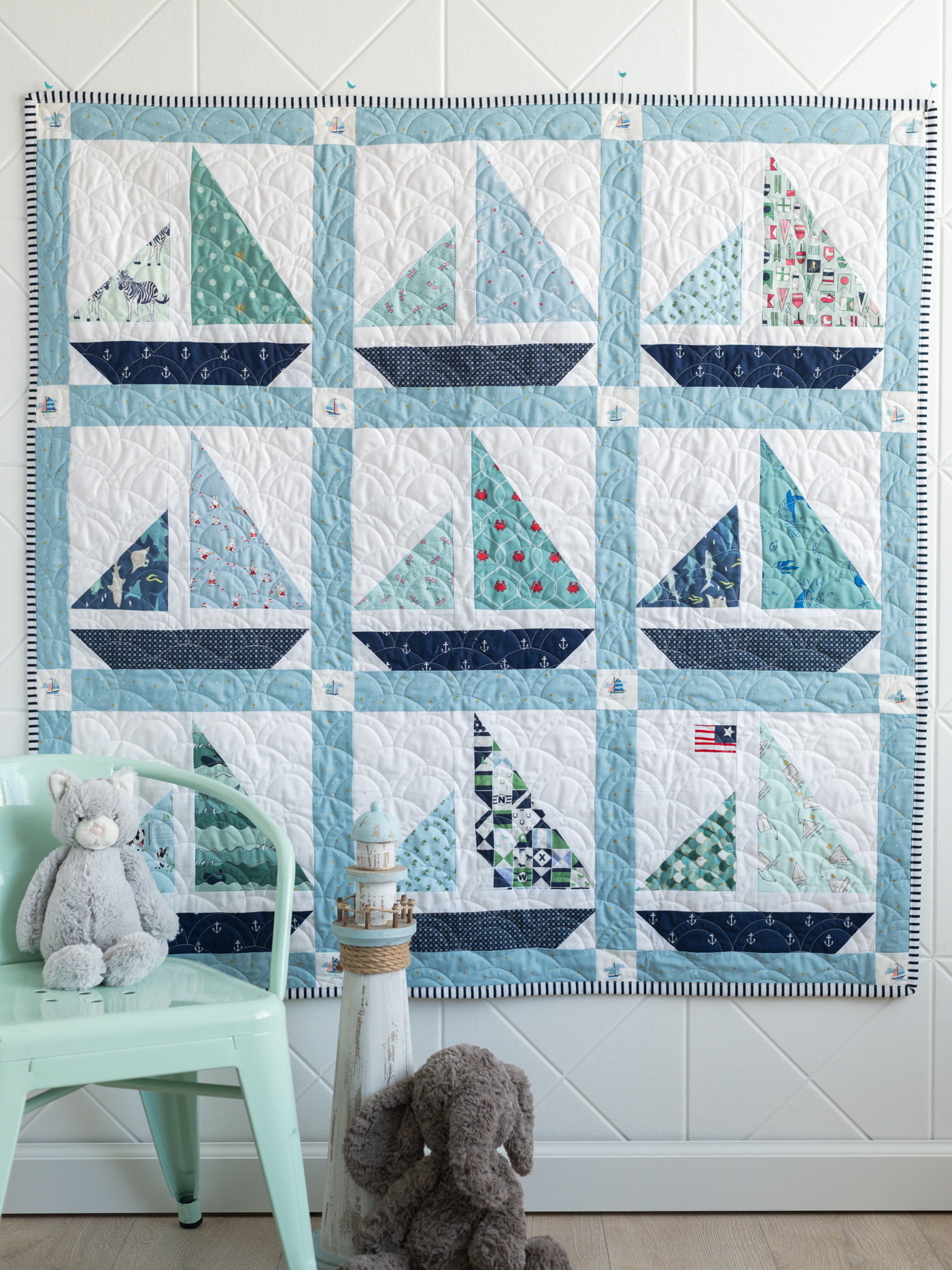 blue and white baby sailboat quilt hanging on wall