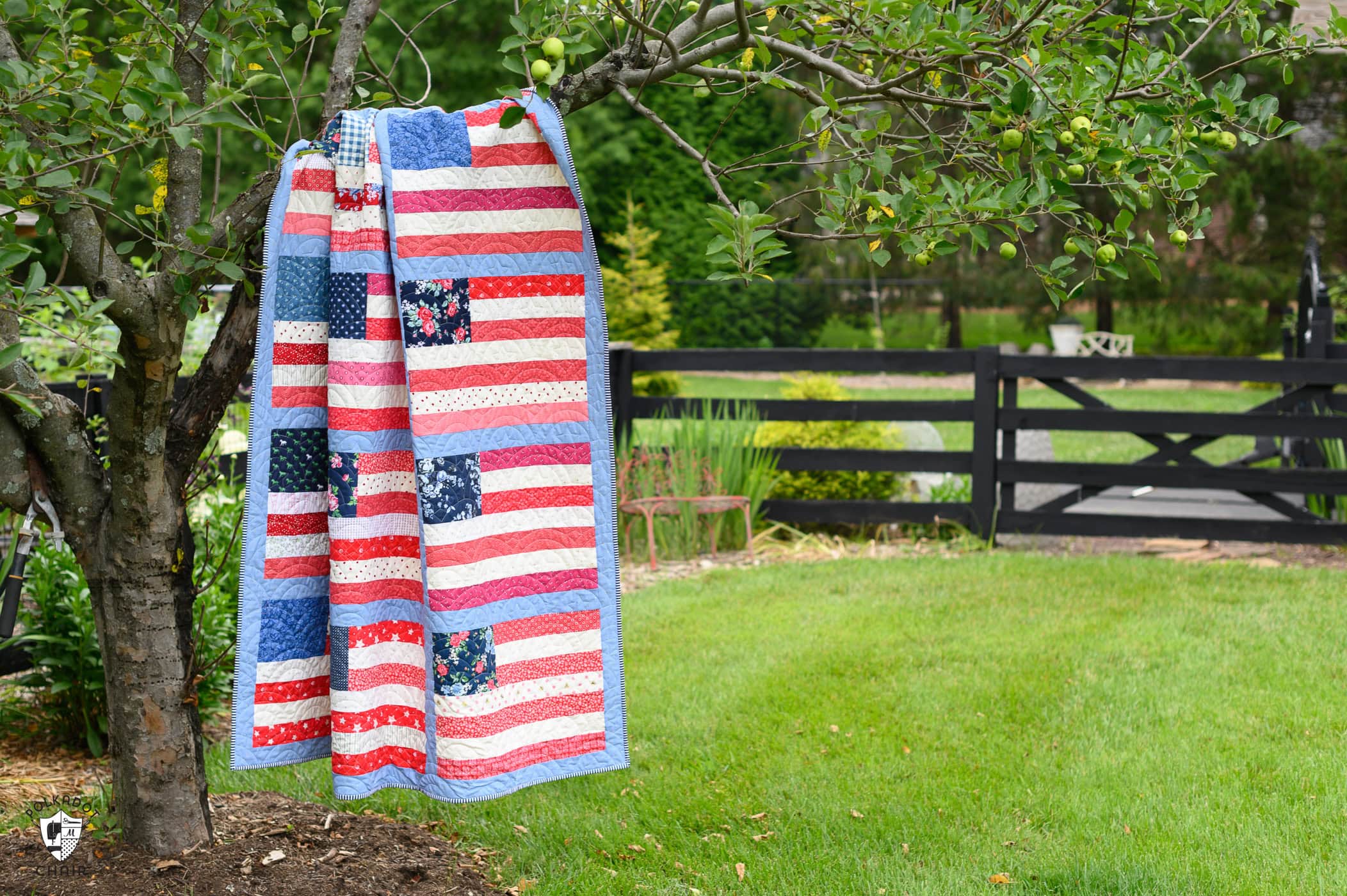 American flag quilt hanging on tree outdoors