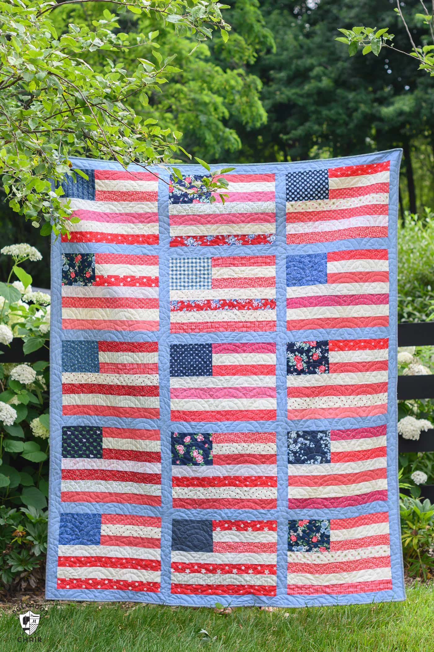 Red white and blue american flag quilt outdoors in front of a tree