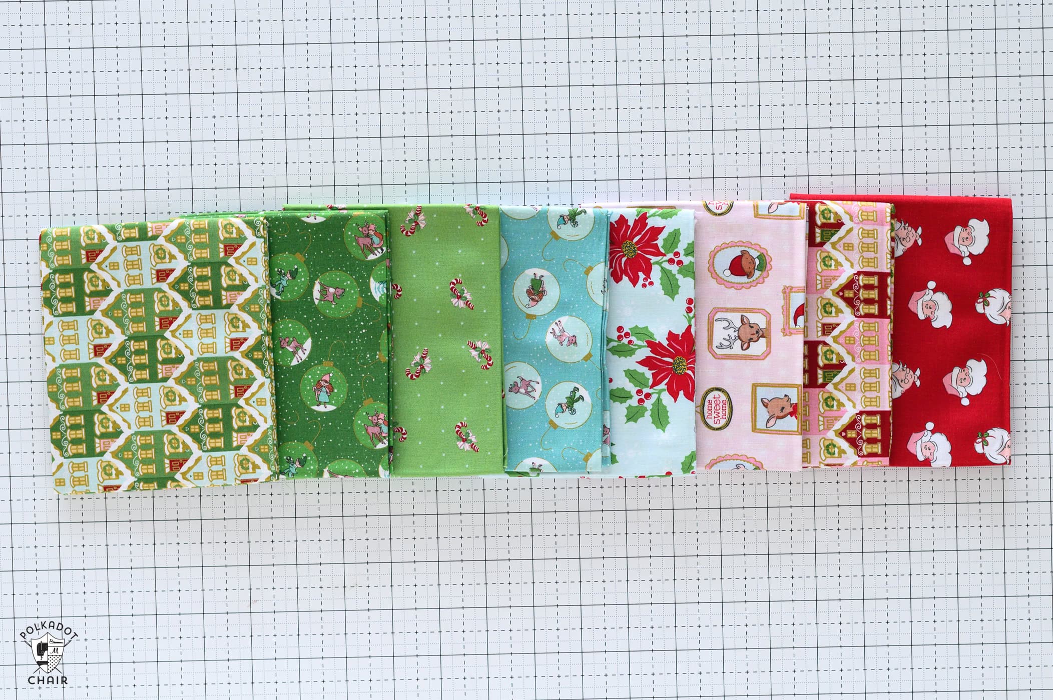 green, aqua, pink and red christmas fabric fat quarters on white cutting mat