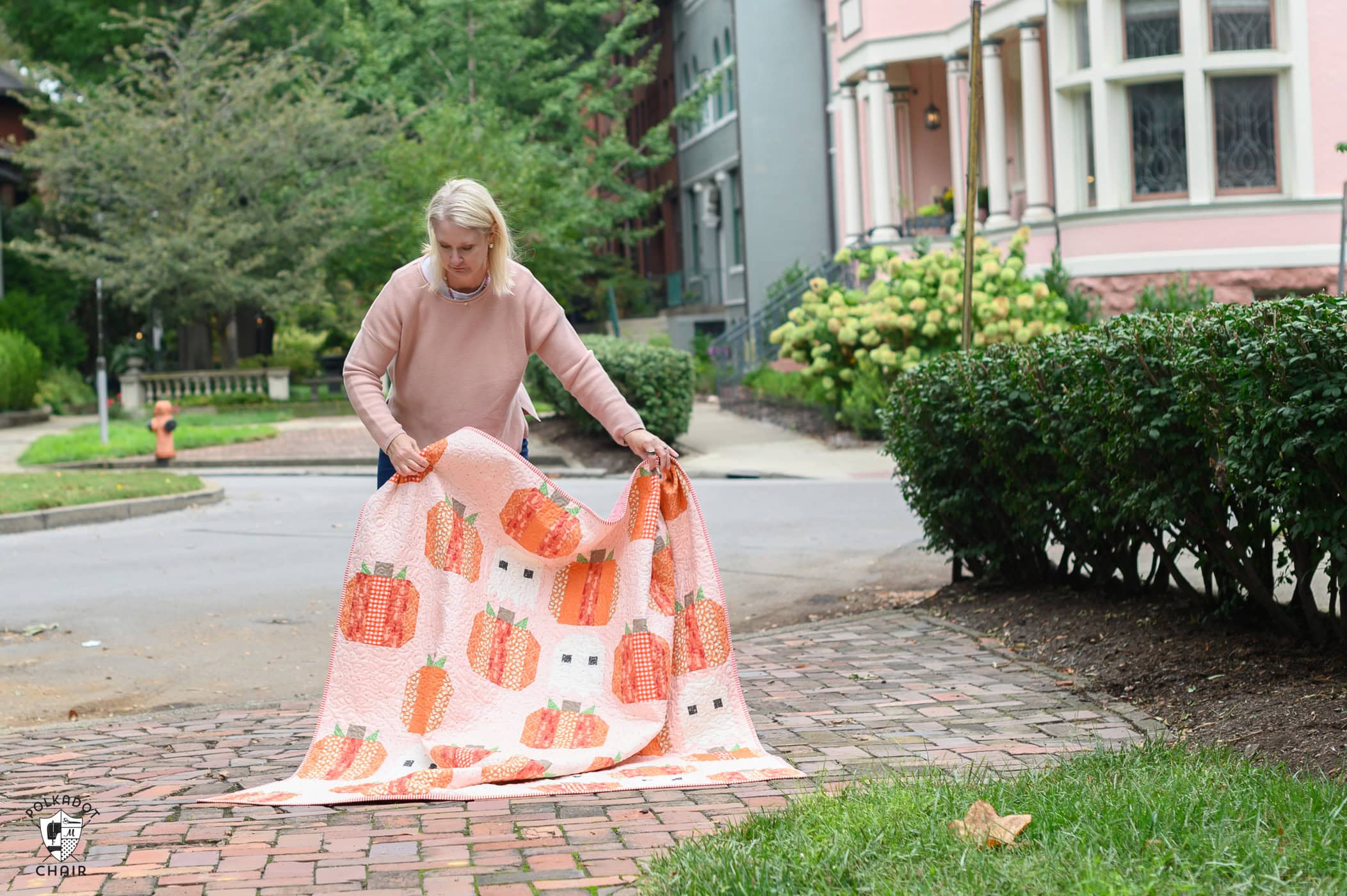 woman holding pink and orange halloween quilt outdoors