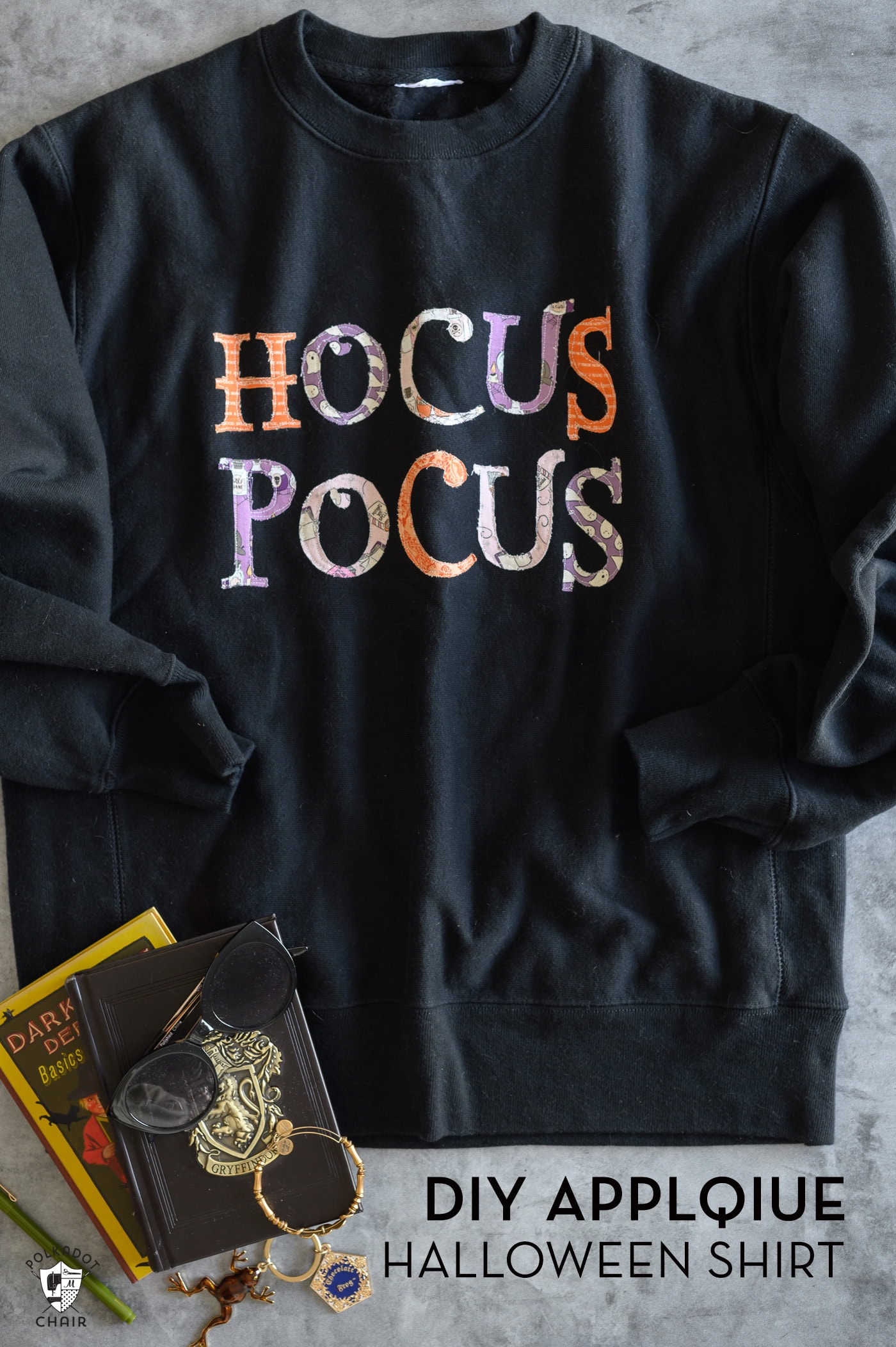 Black sweatshirt with pink, orange and purple hocus pocus lettering on gray table