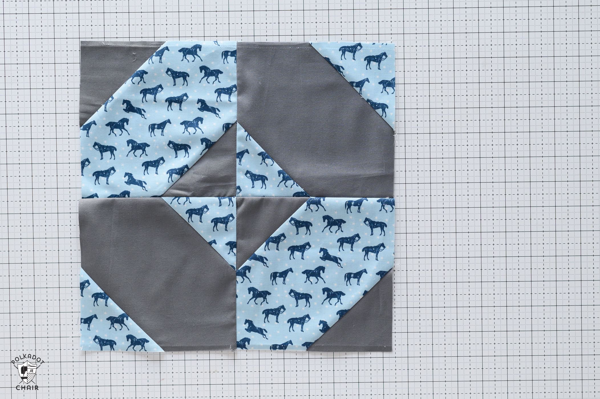 gray and blue quilt block on white cutting mat with sewing notions
