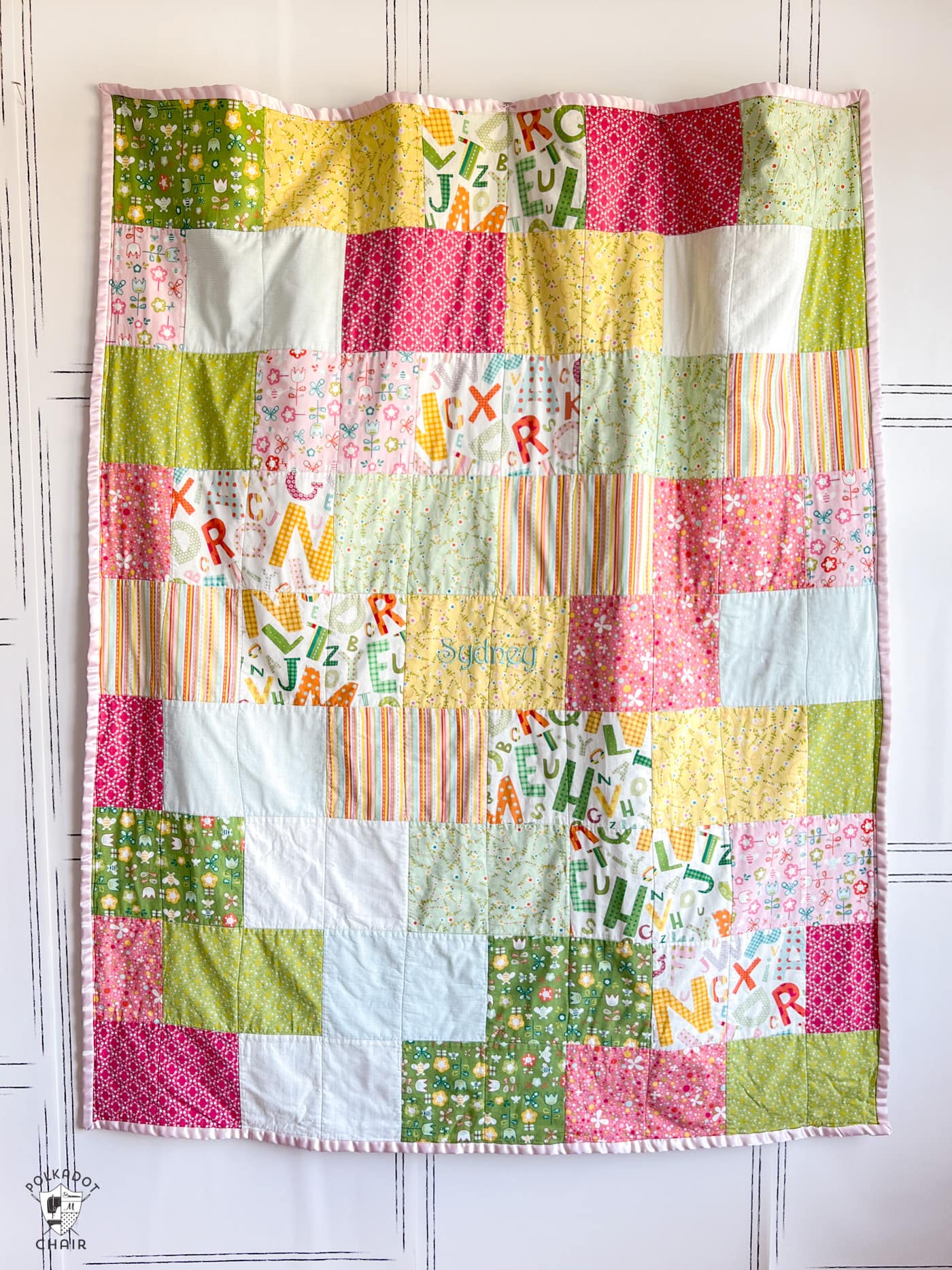pink, green, yellow and red quilt hanging on wall
