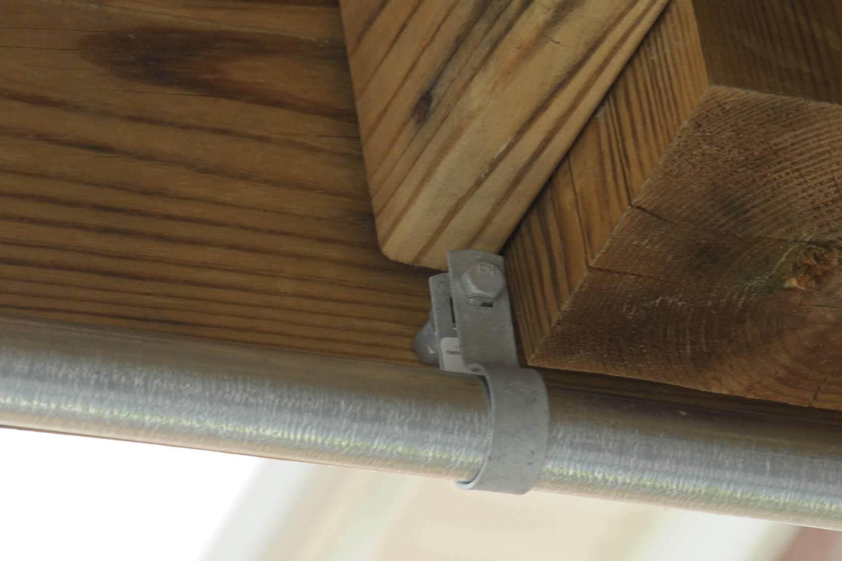 close up of chain link fencing curtain rod attached to wood deck