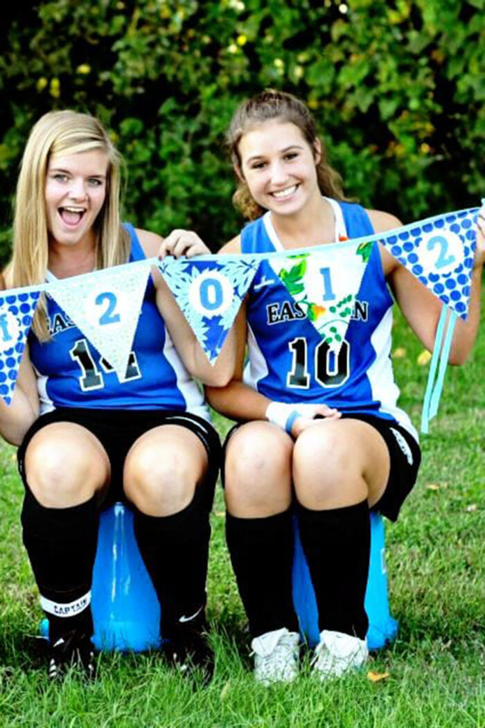 teenagers holding blue and green fabric pennant outdoors
