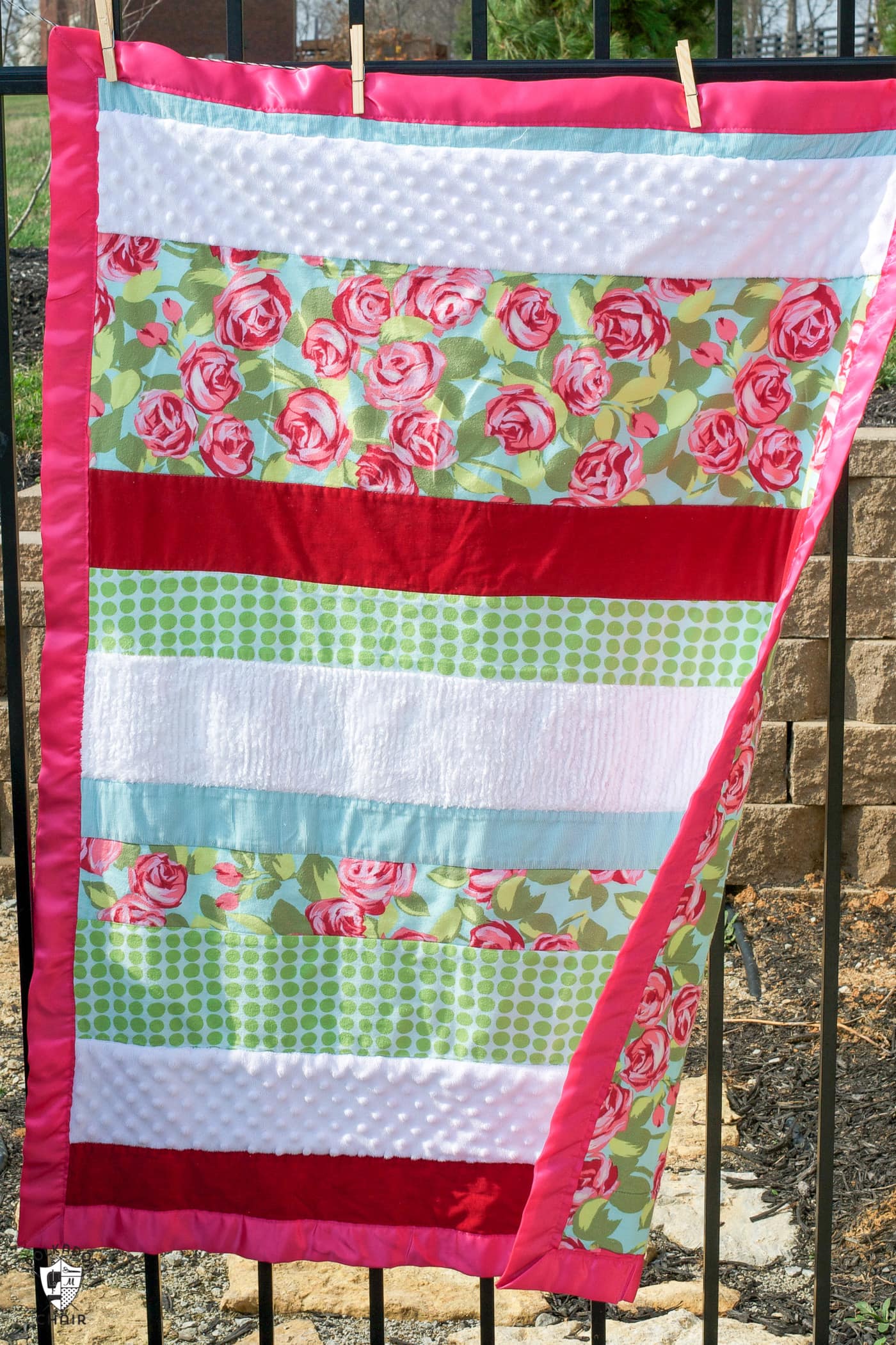 sensory strip baby quilt hanging on fence outside.