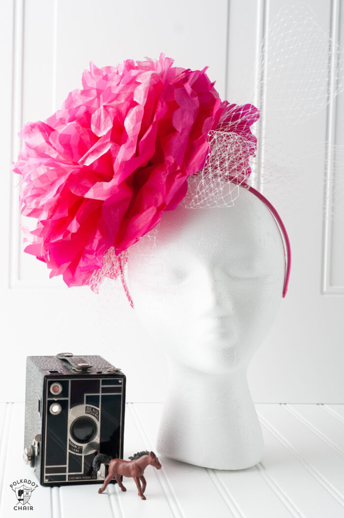 pink paper flower fascinator on white head on white background