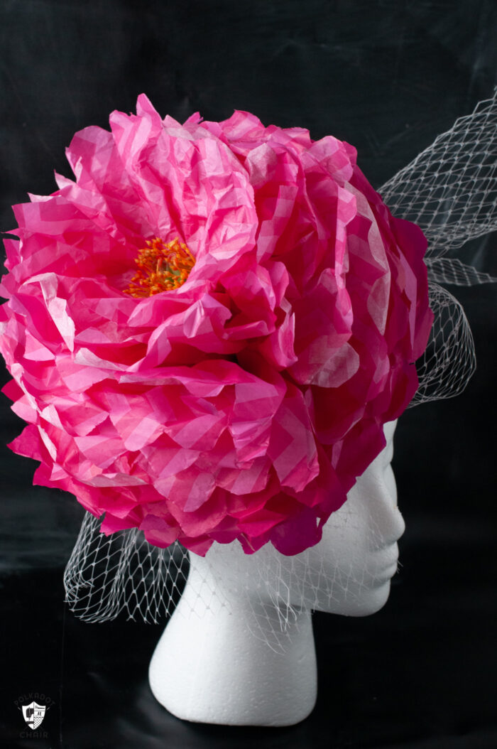 pink paper flower fascinator on white head on black background