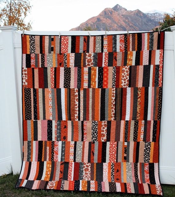 Black and orange halloween quilt hanging on fence