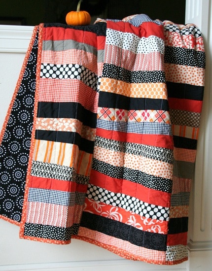 Black and orange halloween quilt hanging on white wall