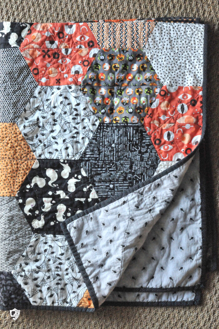 close up of large hexagon quilt with orange, ivory and gray blocks