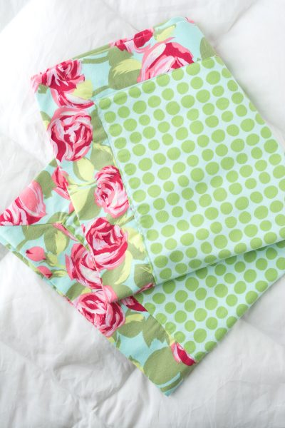 green polkadot and floral flannel blanket folded on white quilt
