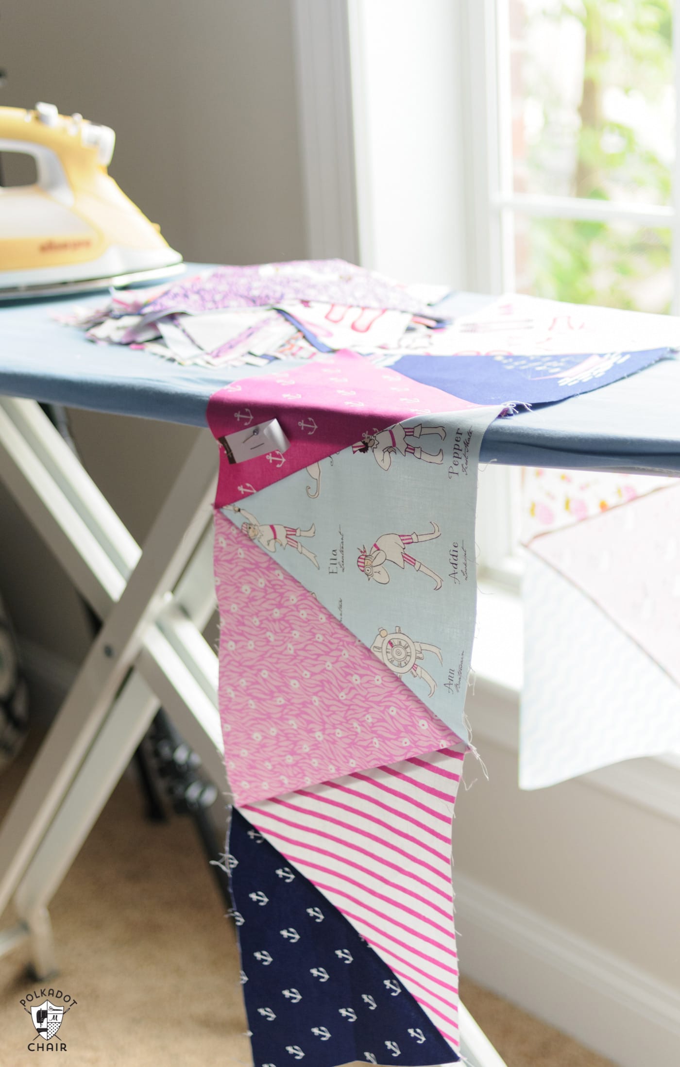 pink and blue fabric on ironing board with iron