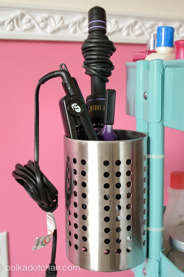 silver canister with black and purple curling iron attached to side of blue cart. 