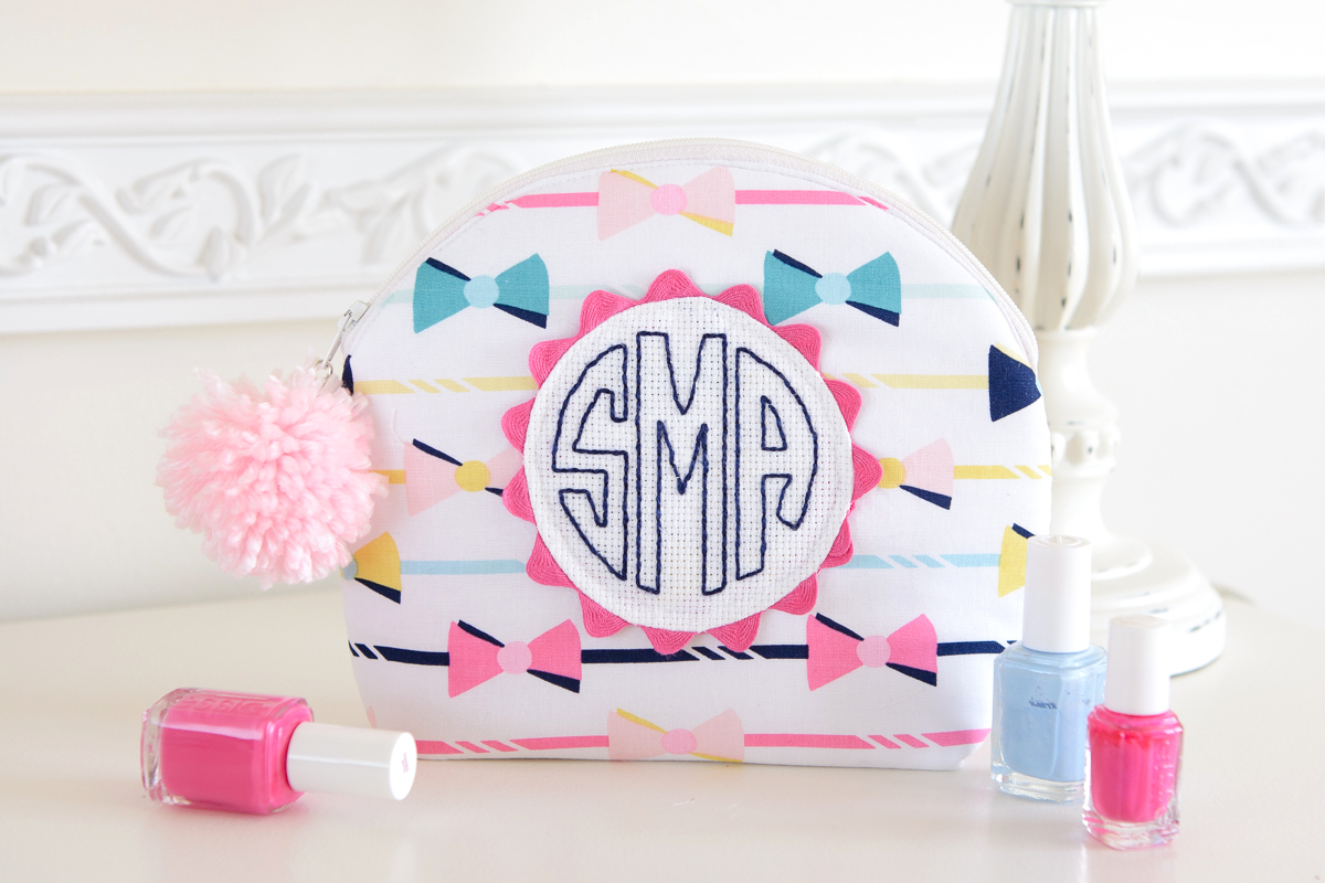 Make up pouch next to nail polish on white table.